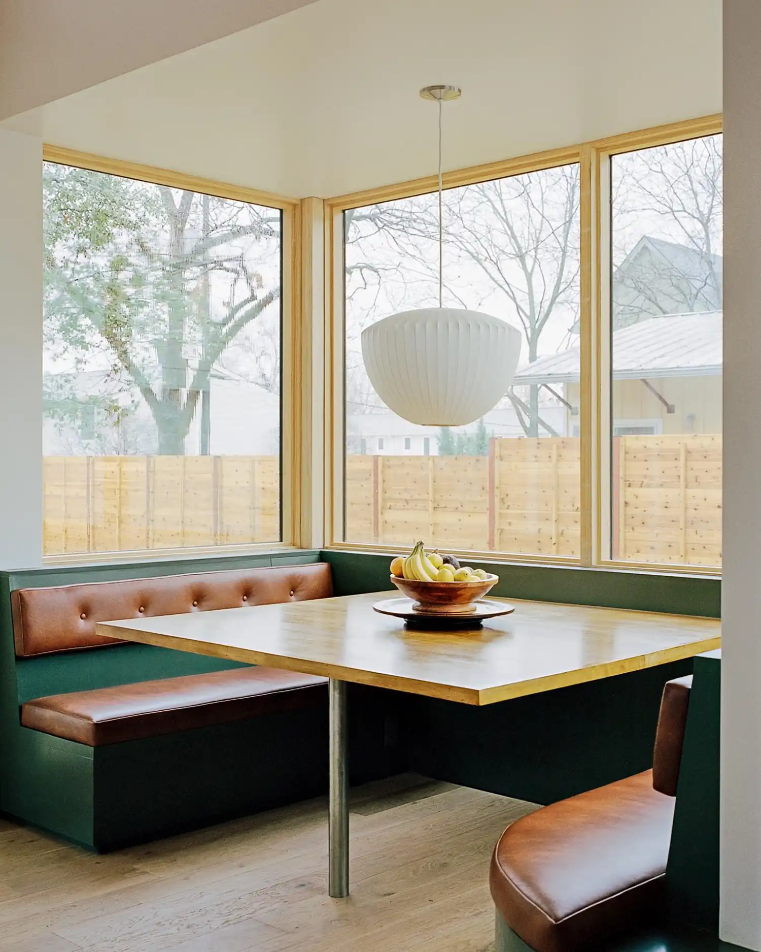 Close-up of a modern dining booth with a white pendant lamp and timber table.