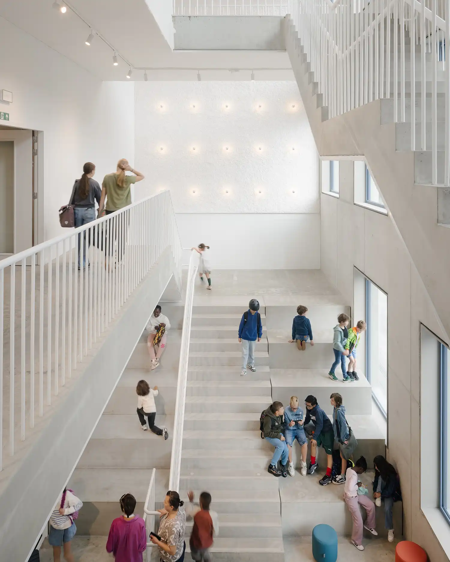 A wide concrete staircase used as a social seating area by students in a bright atrium.