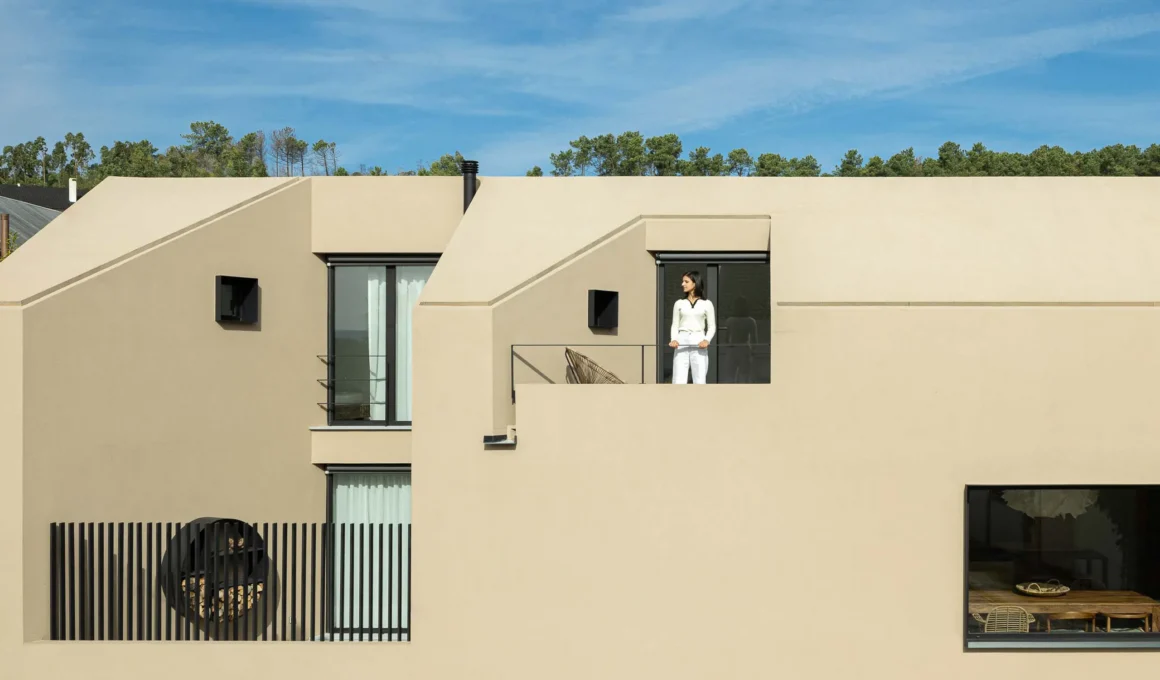 Geometric facade of Casinha Da Melroeira with a person on the balcony