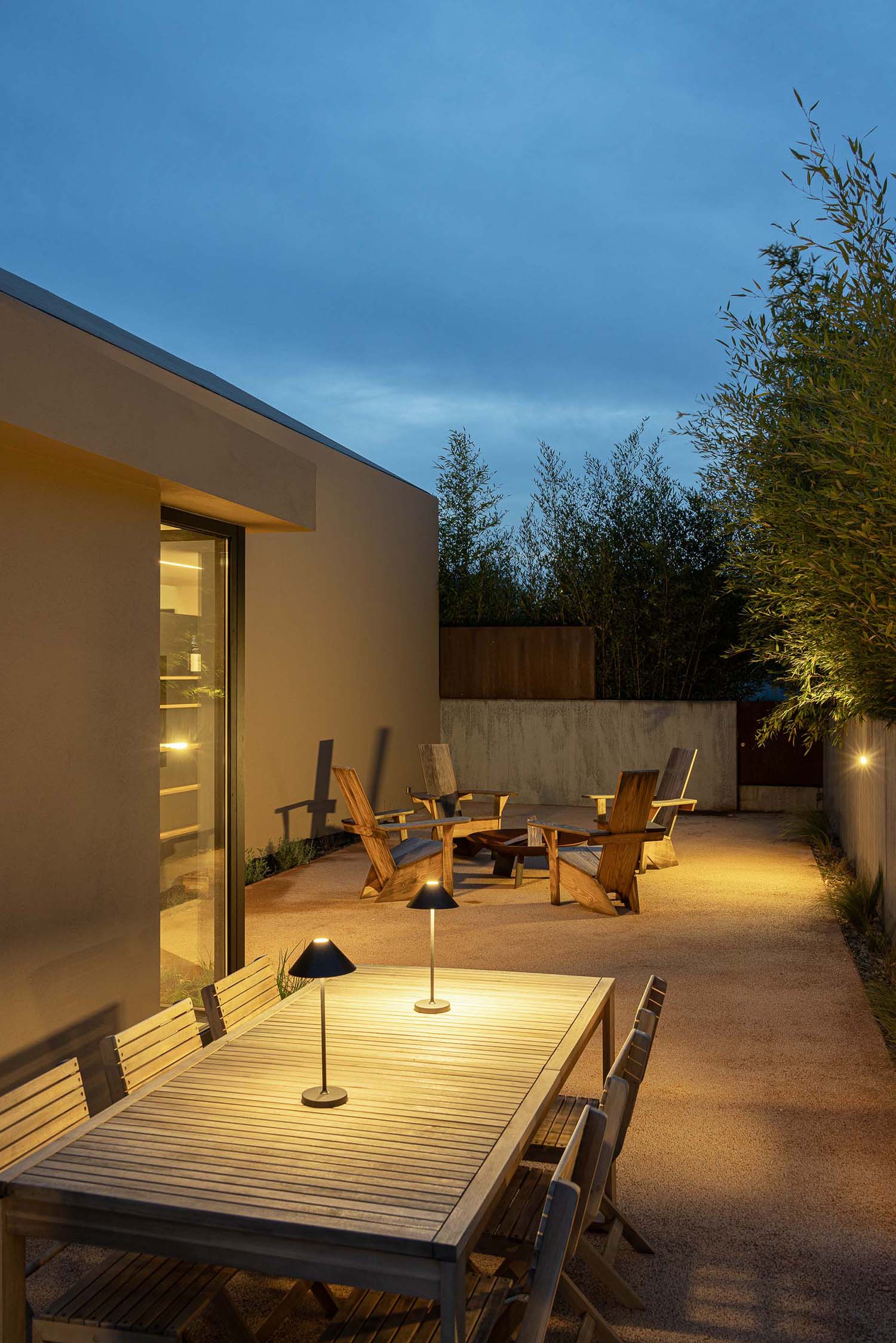 Outdoor patio at twilight with wooden furniture and warm lighting