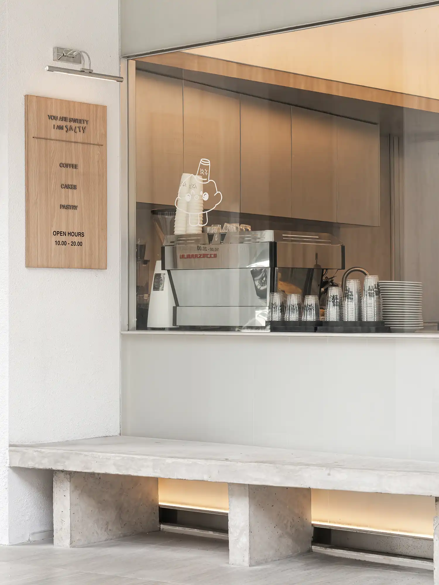 Concrete exterior bench and coffee bar window with a service menu.