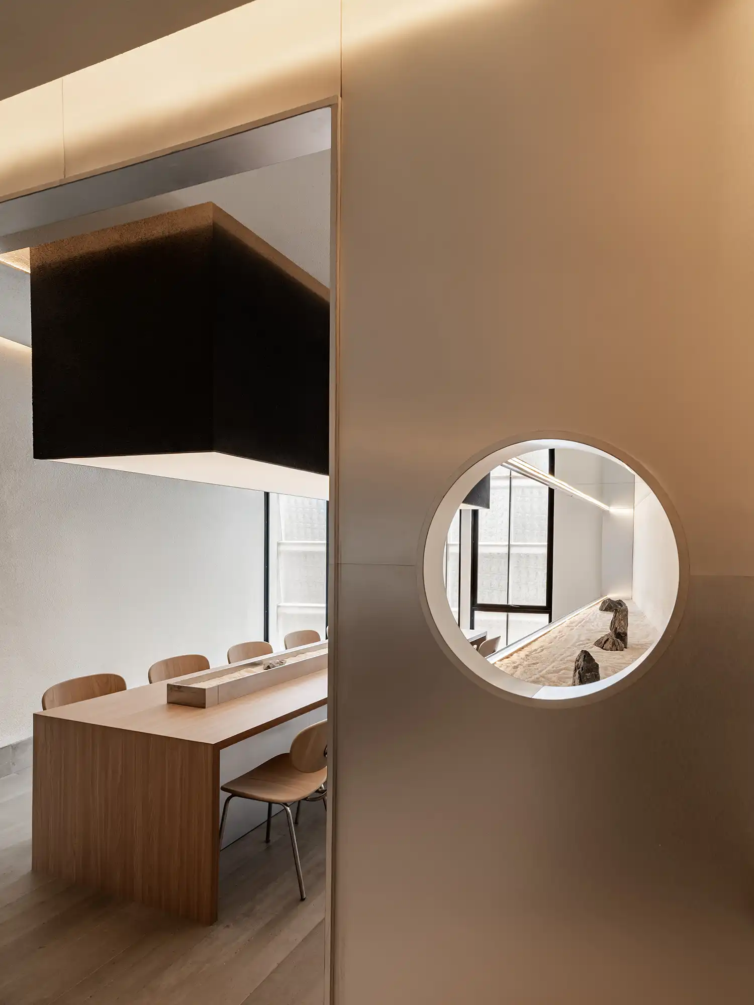 A circular porthole window looking from a grey wall into the timber seating area.