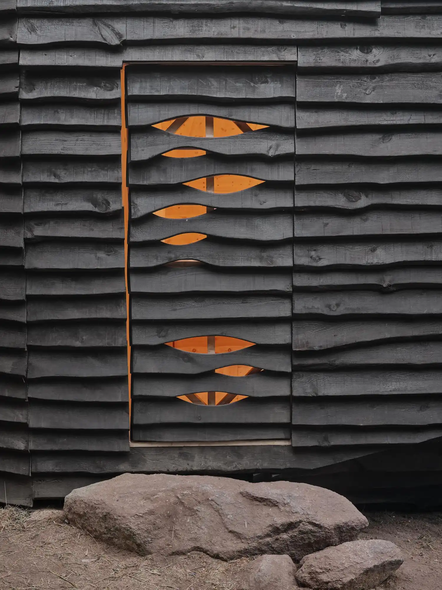 Detail of charred wood cladding and carved stone entrance