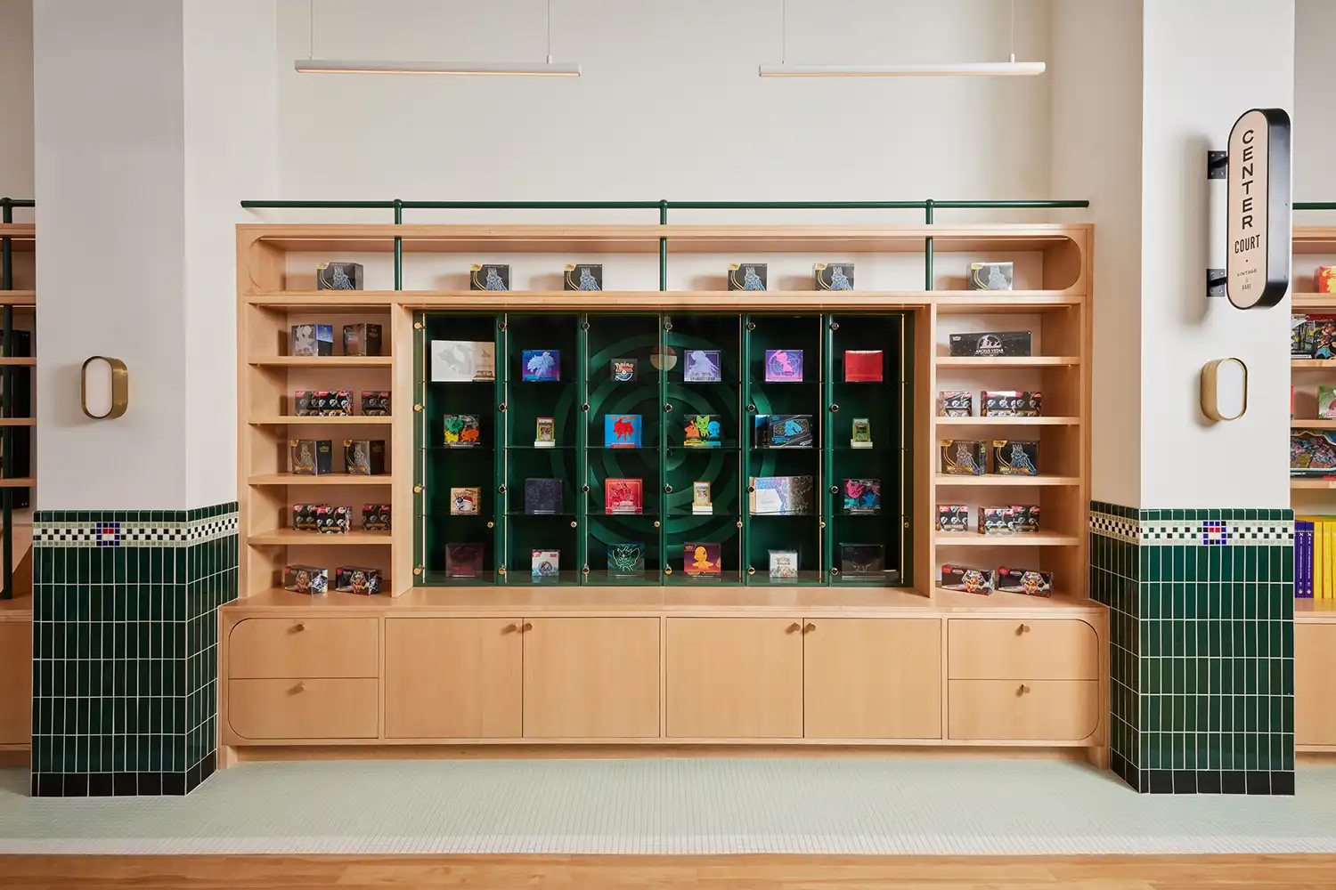 Maple wood retail shelving with a central green display case and brass accents.