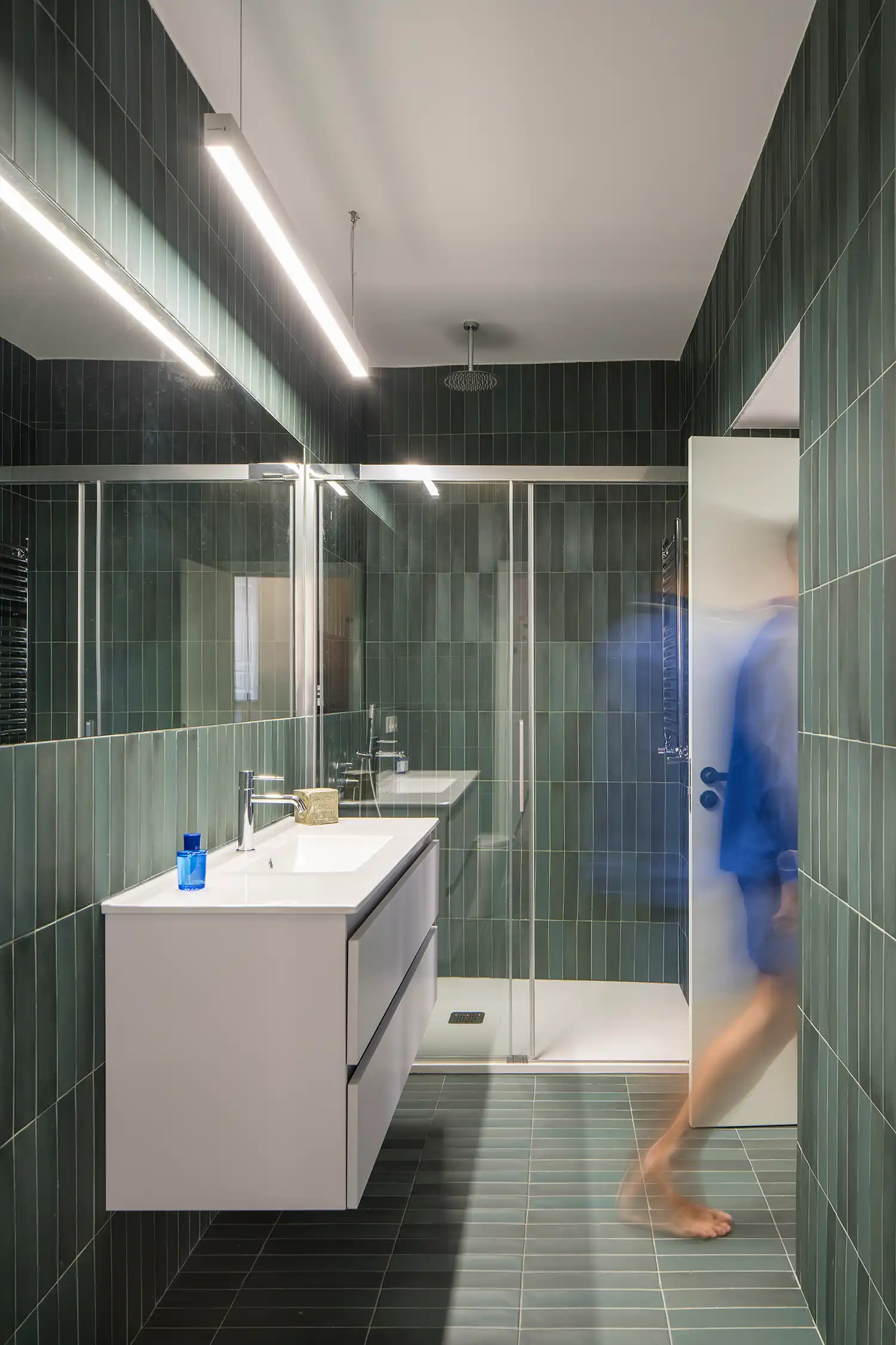 Modern bathroom with vertical green tiles and white floating vanity
