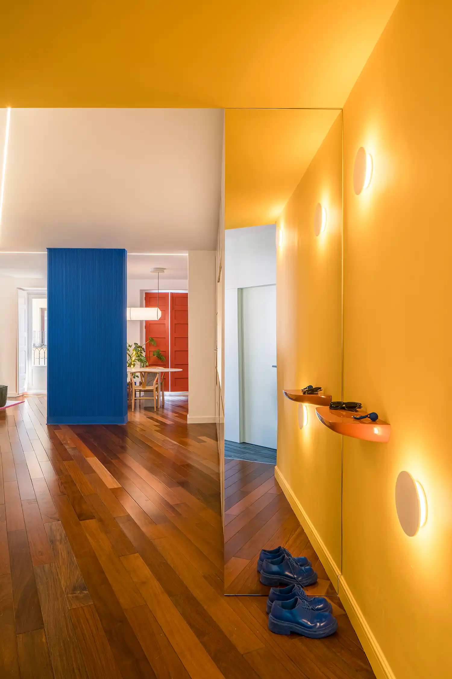 Yellow hallway with mirrored wall and floating orange shelves