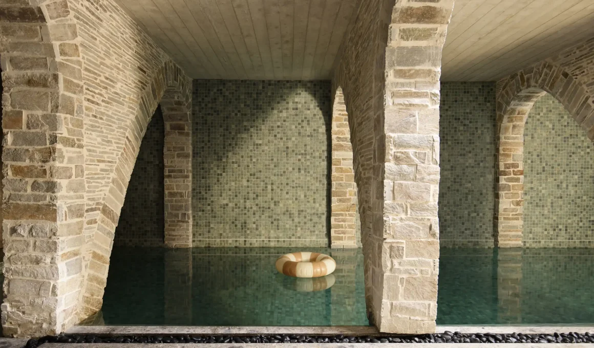Subterranean swimming pool with sandstone parabolic arches and green mosaic tiles in a Sydney home.