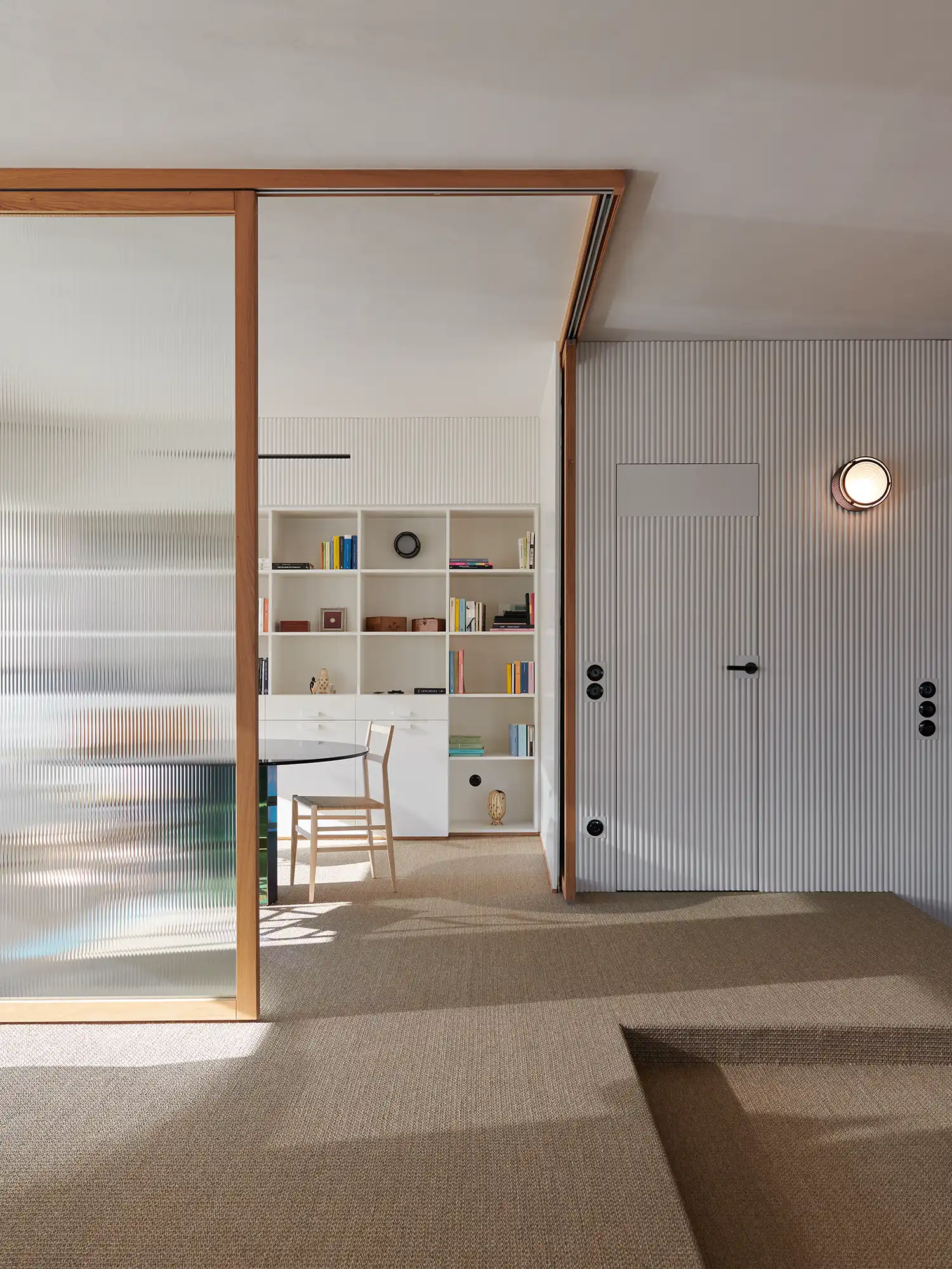 Ribbed wooden wall paneling and translucent glass sliding screens in a contemporary hallway.