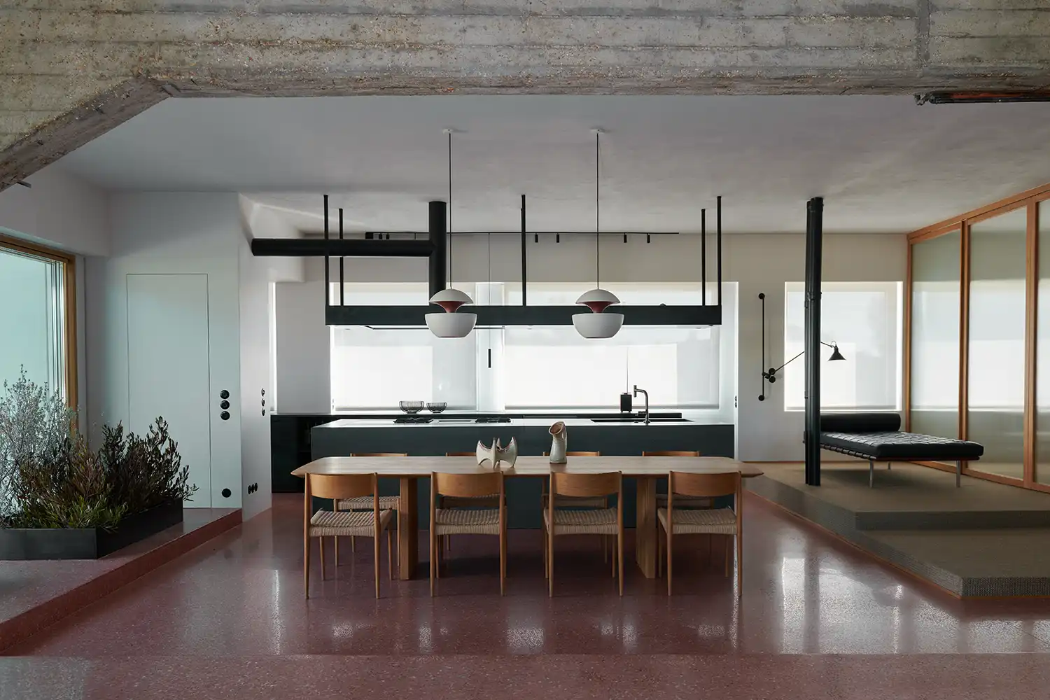 Open-plan kitchen and dining area with red crushed brick floors and a large wooden dining table.