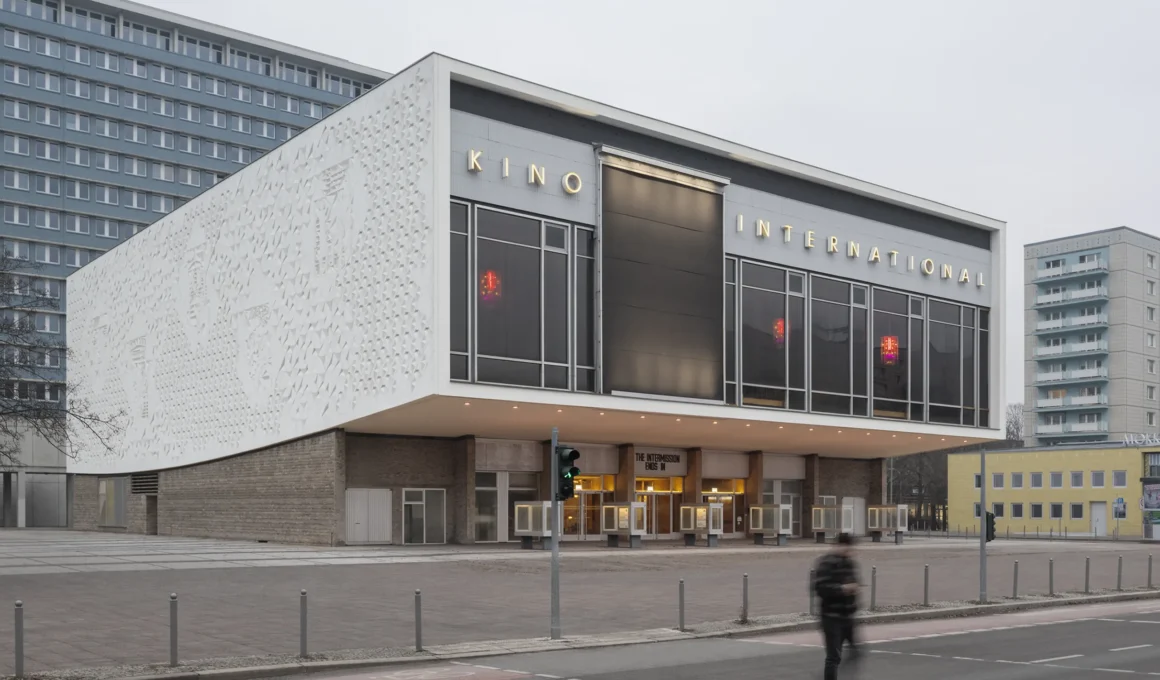 Wide exterior view of Kino International in Berlin featuring a cantilevered upper floor and a large glass facade.