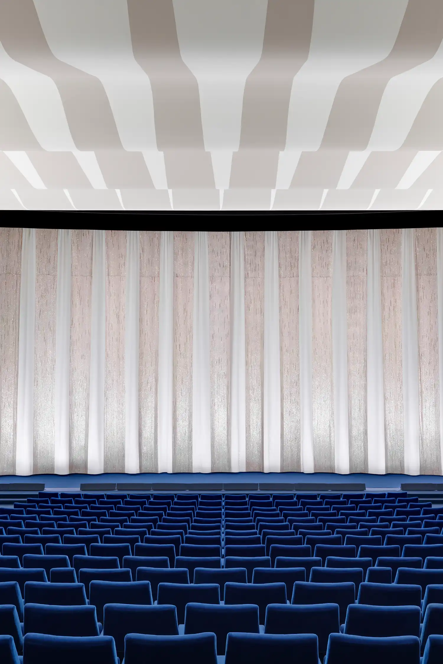 Interior view of the cinema auditorium with vibrant blue seating and the restored silver premiere curtain.