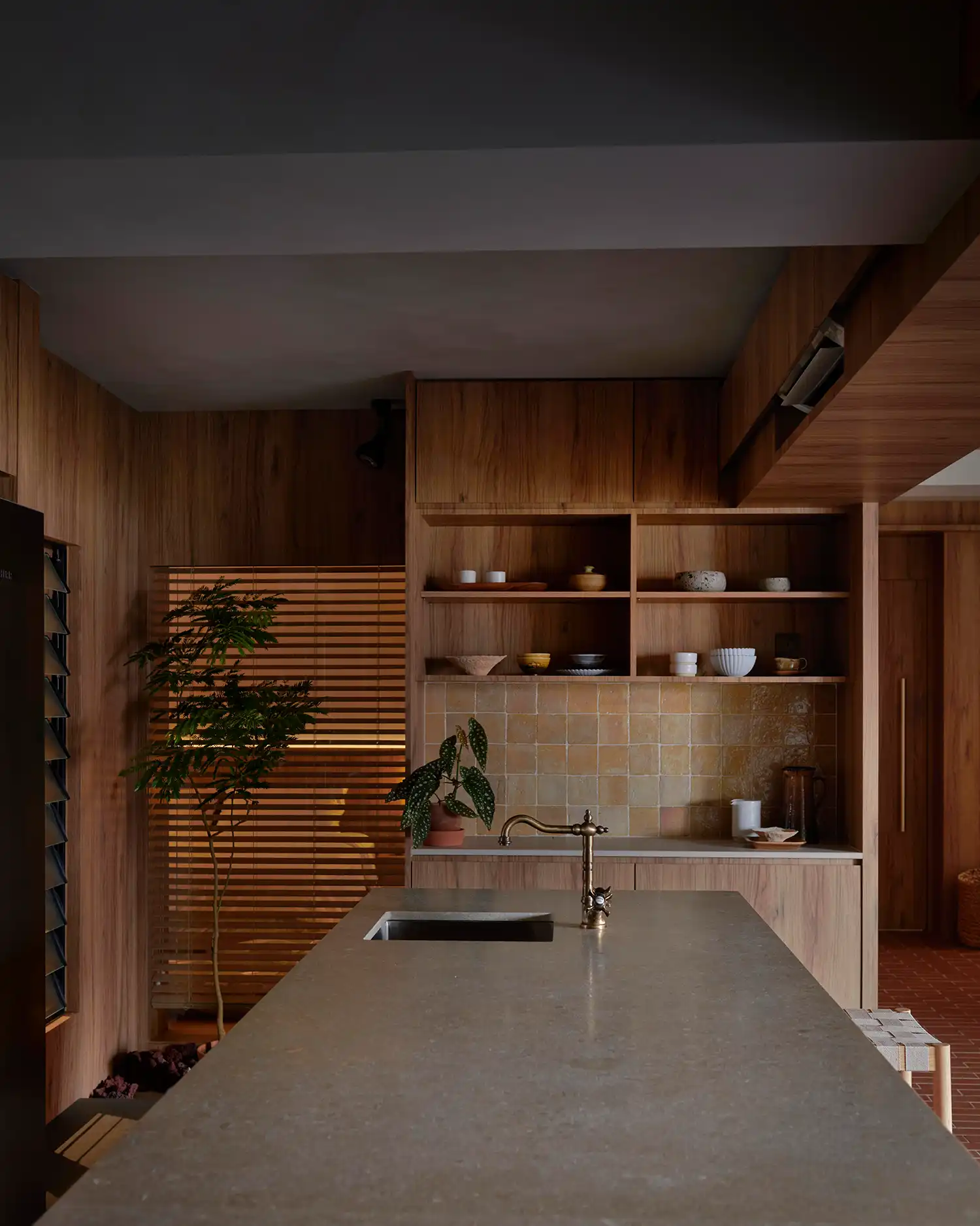 Modern kitchen island with a brass faucet and wooden cabinetry in a renovated Singapore home.