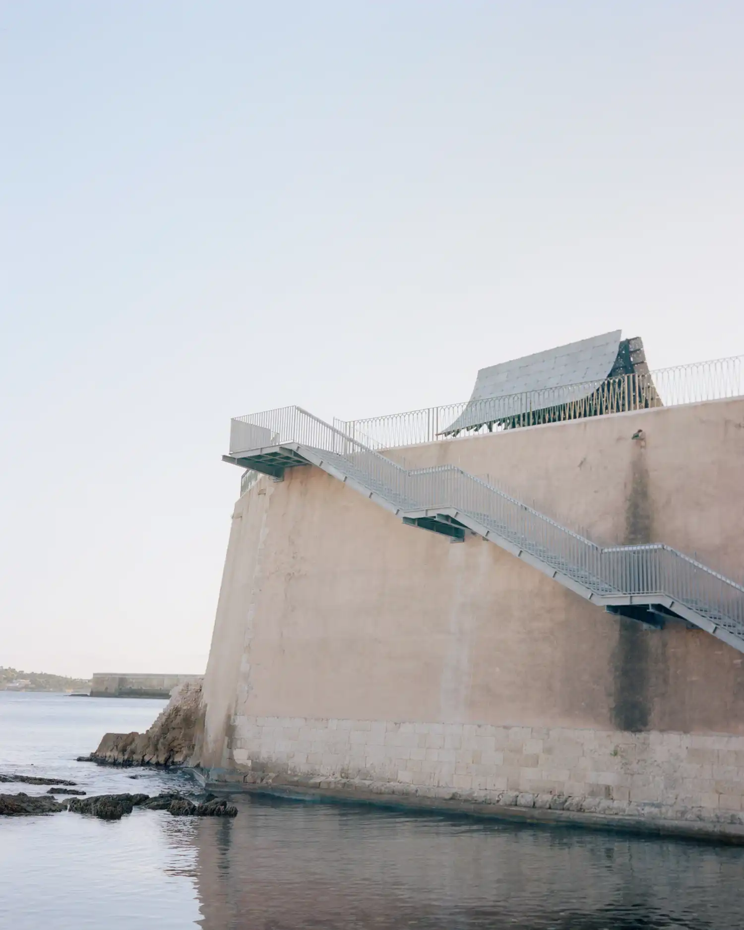 Low angle view of Asympta pavilion atop a historic stone bastion in Ortigia