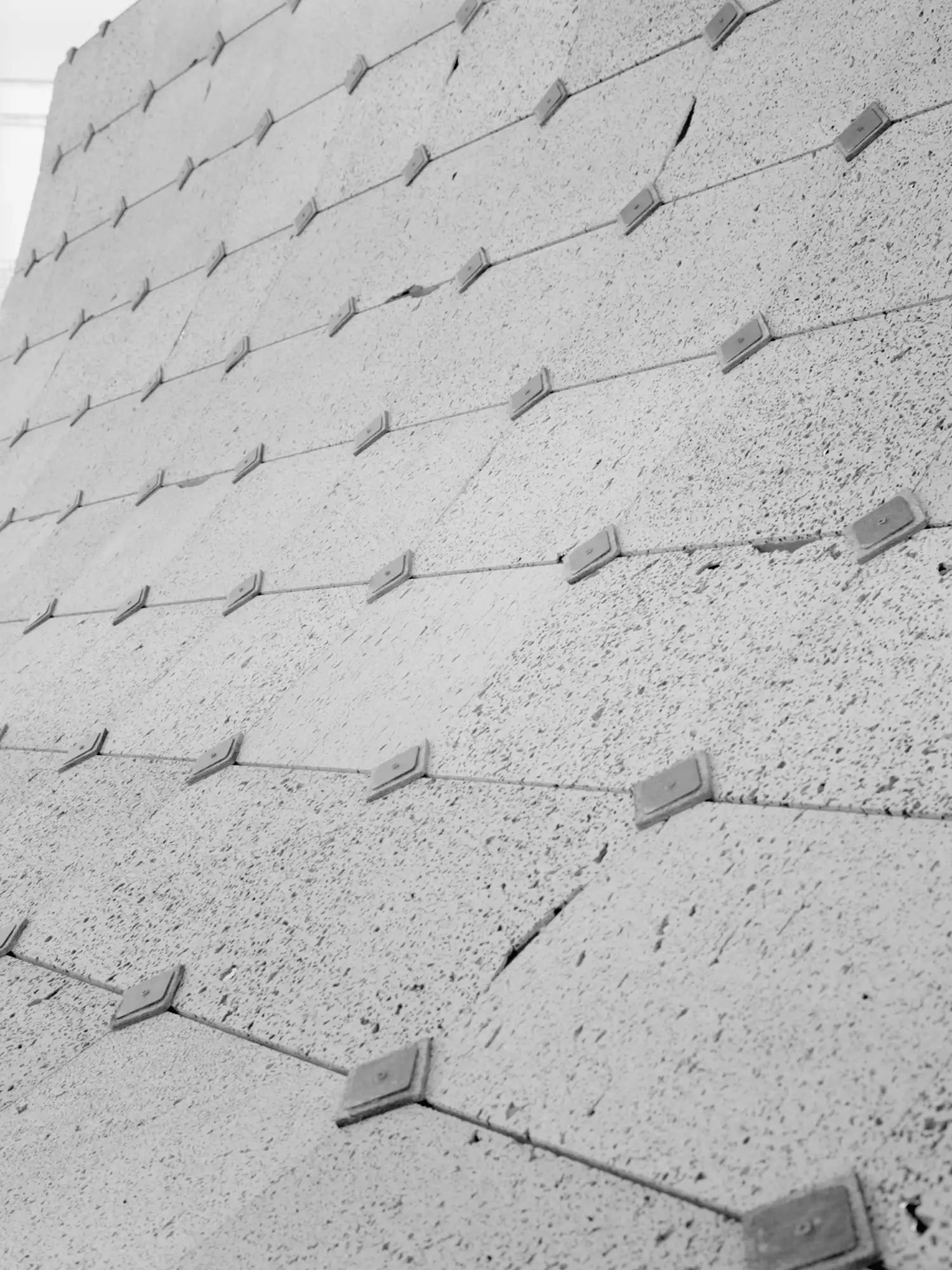 Macro detail of porous grey stone tiles on the roof of Asympta