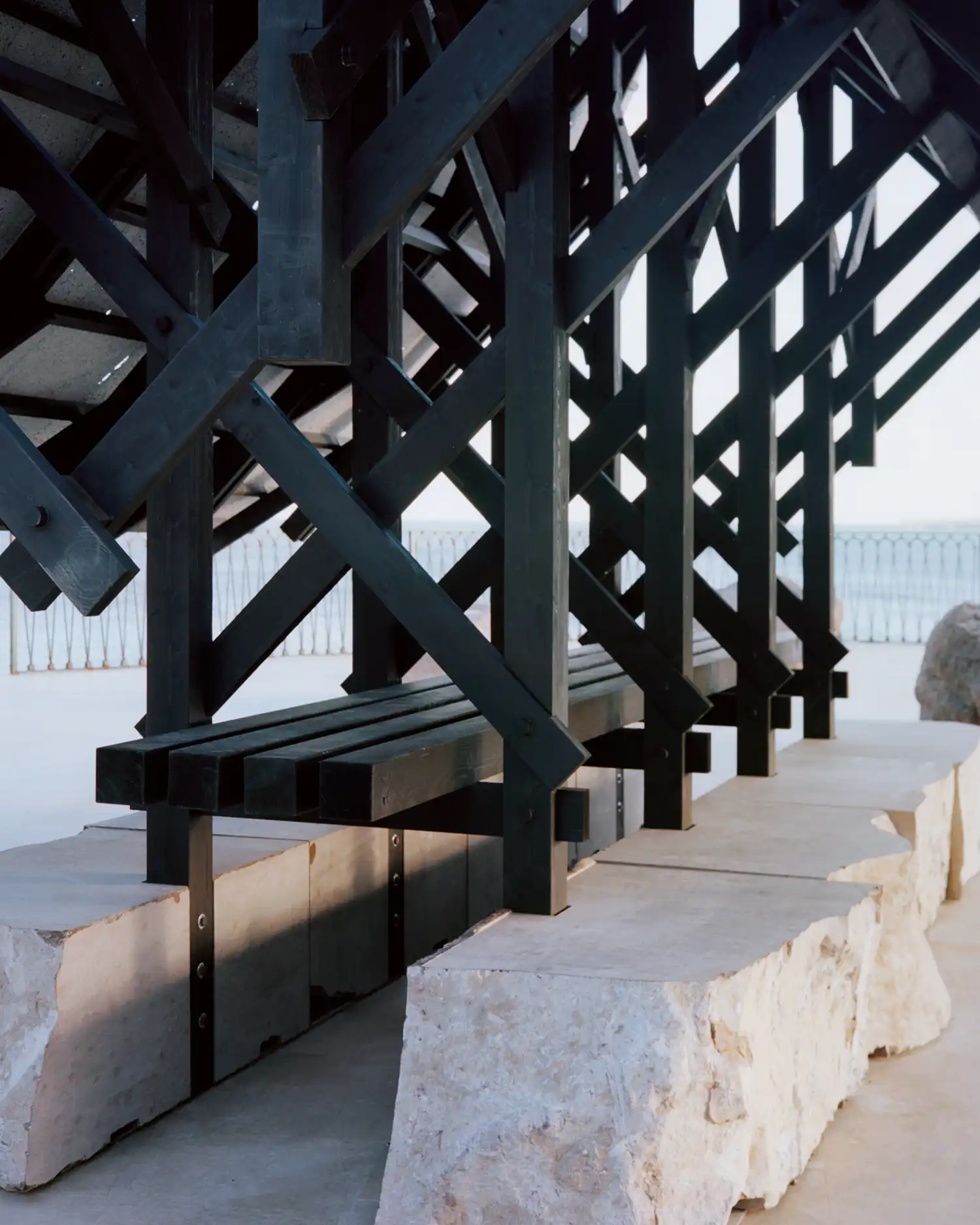 Interior view of scorched timber beams and limestone seating in Asympta