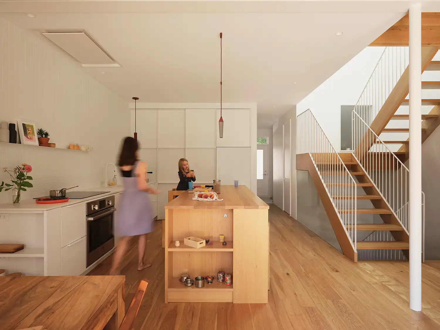 View from the dining area towards the white oak kitchen island and central staircase.