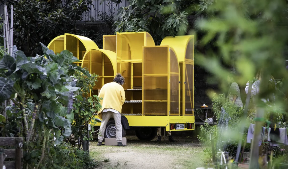 Person tending to seeds inside a yellow mobile greenhouse at Quinta da Armada.