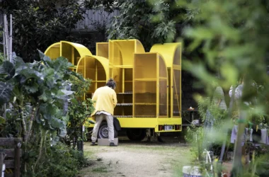 Person tending to seeds inside a yellow mobile greenhouse at Quinta da Armada.