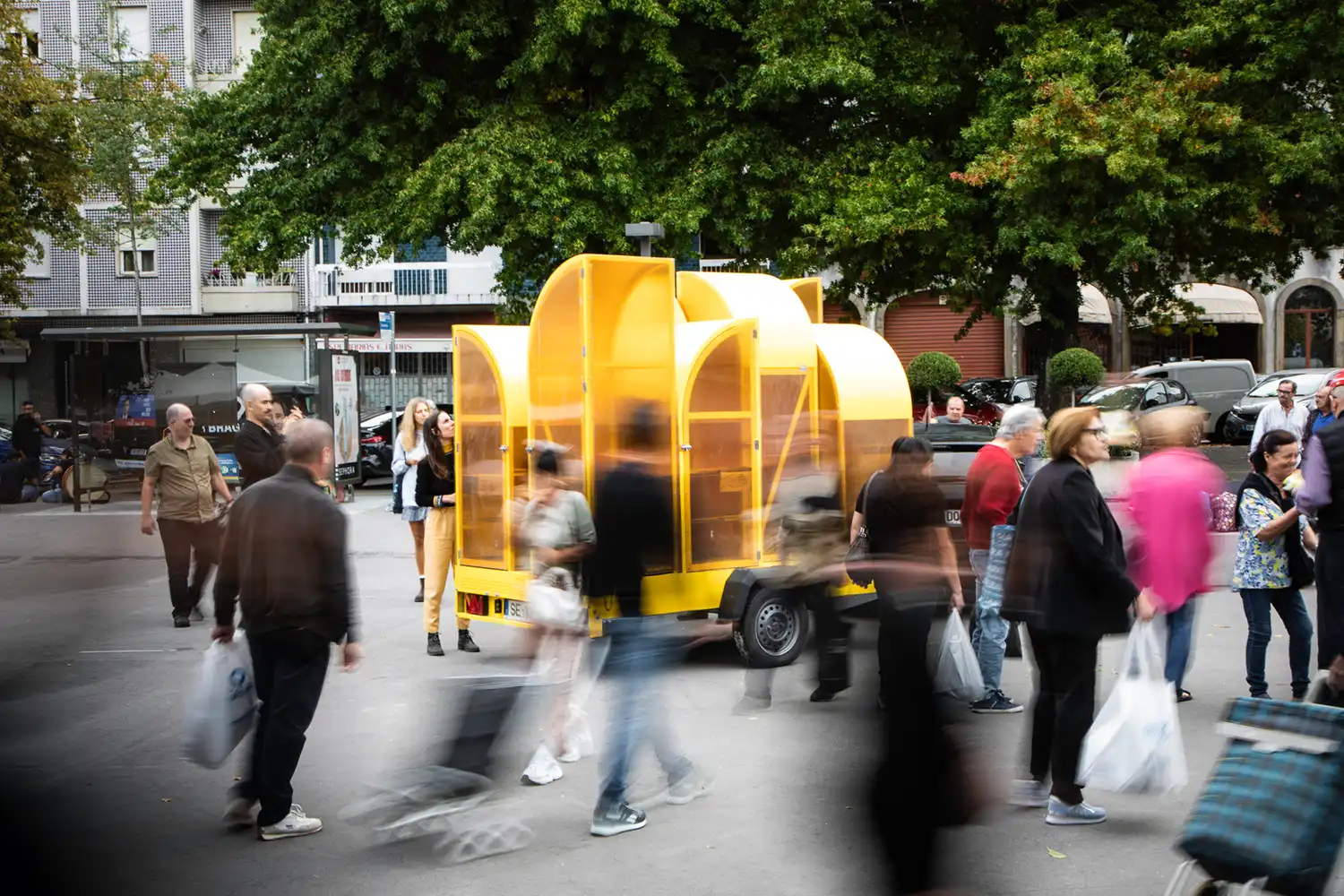 Long exposure of the yellow mobile greenhouse in a busy public square in Braga.