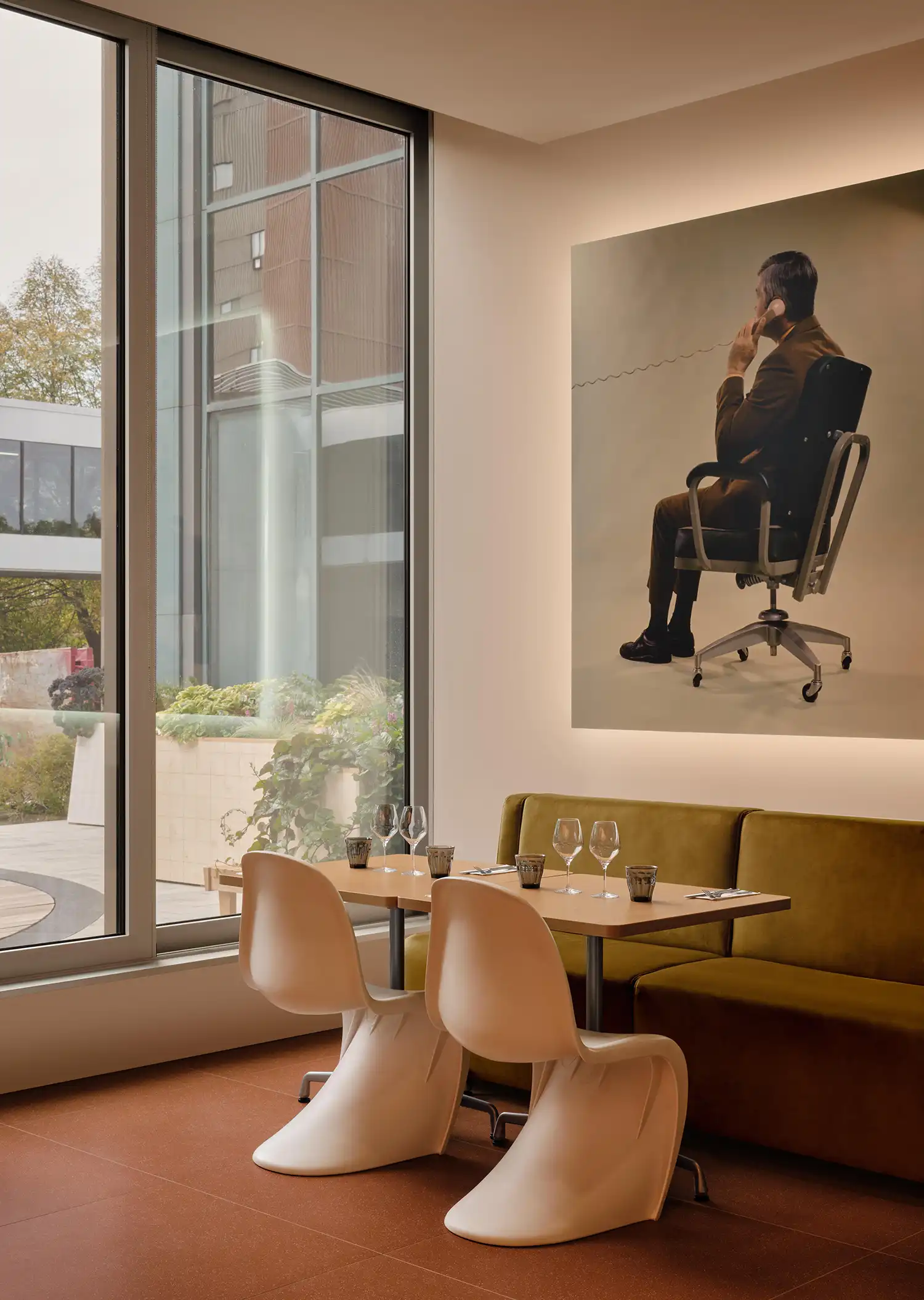 Bistro seating area with white Panton-style chairs and a large mid-century office themed portrait