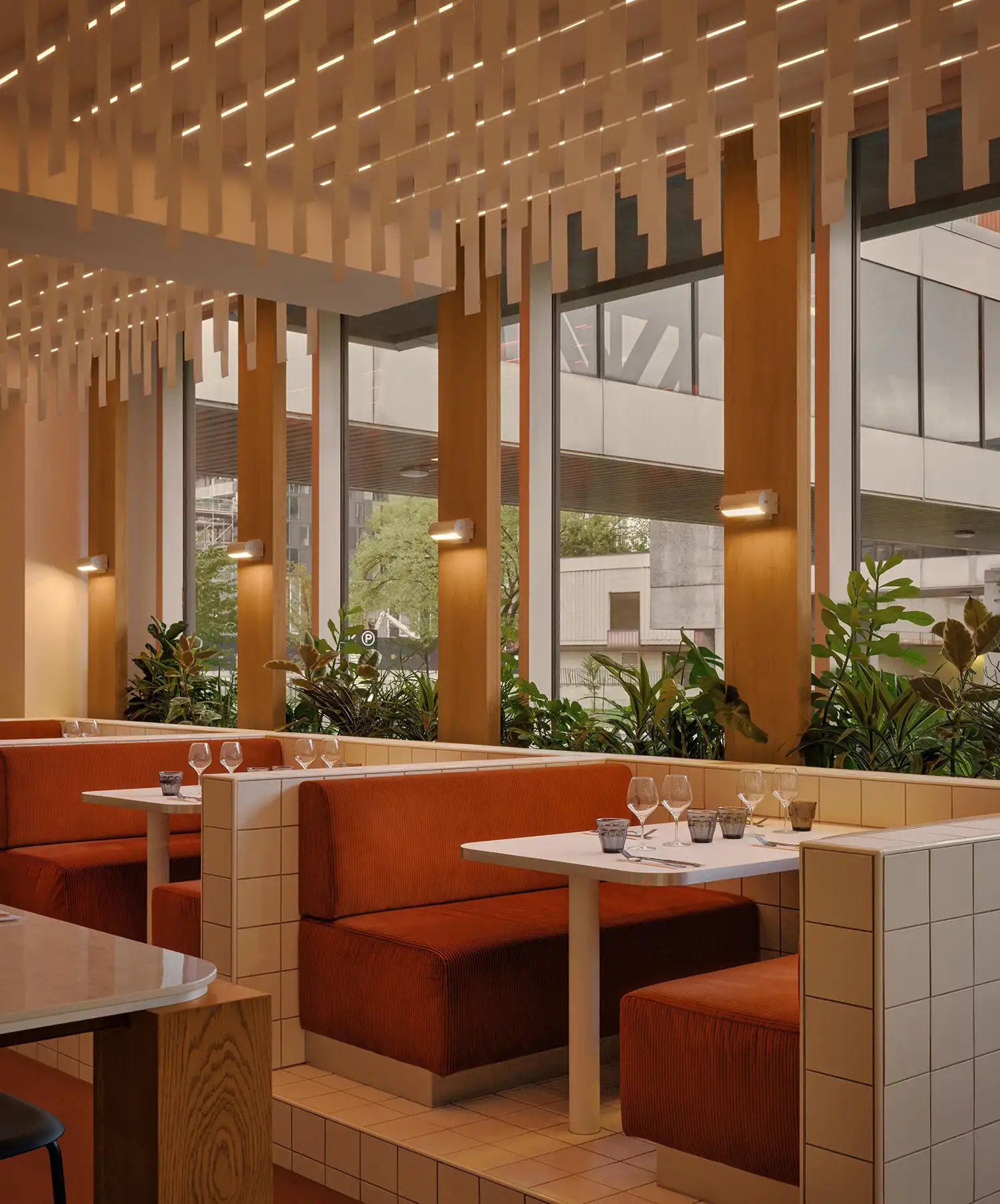 Terracotta velvet booths at Bistro Siège Social separated by white tile partitions