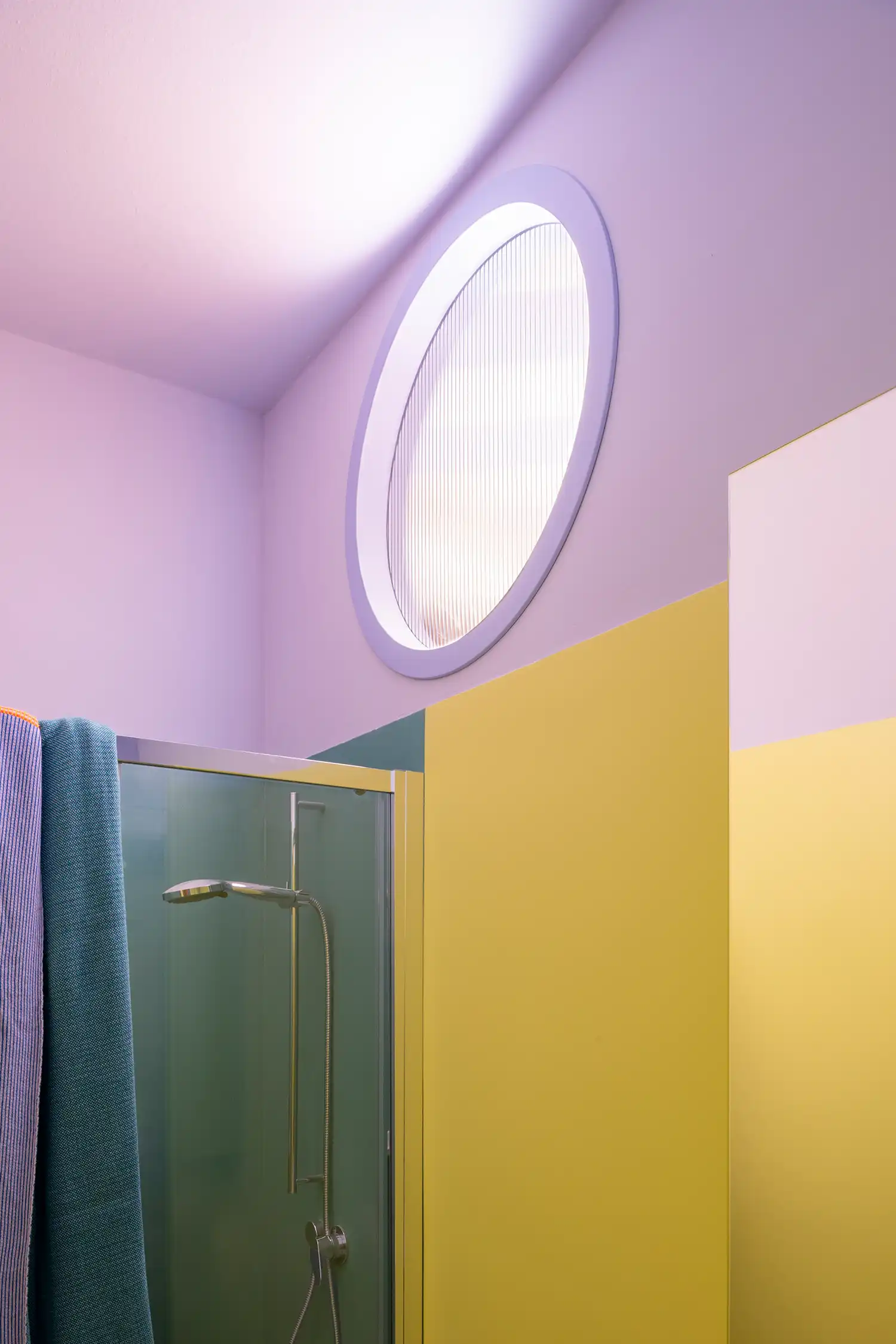 Circular porthole window in a lilac and acid green bathroom