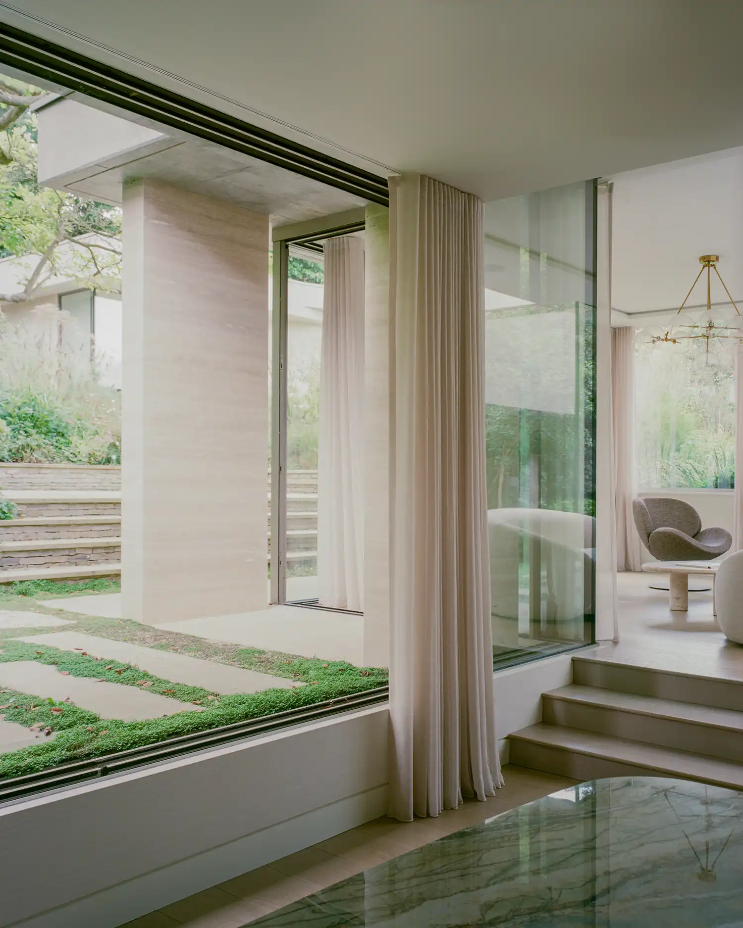 Minimalist interior view showing the transition between a travertine-clad pillar and an outdoor stone courtyard.