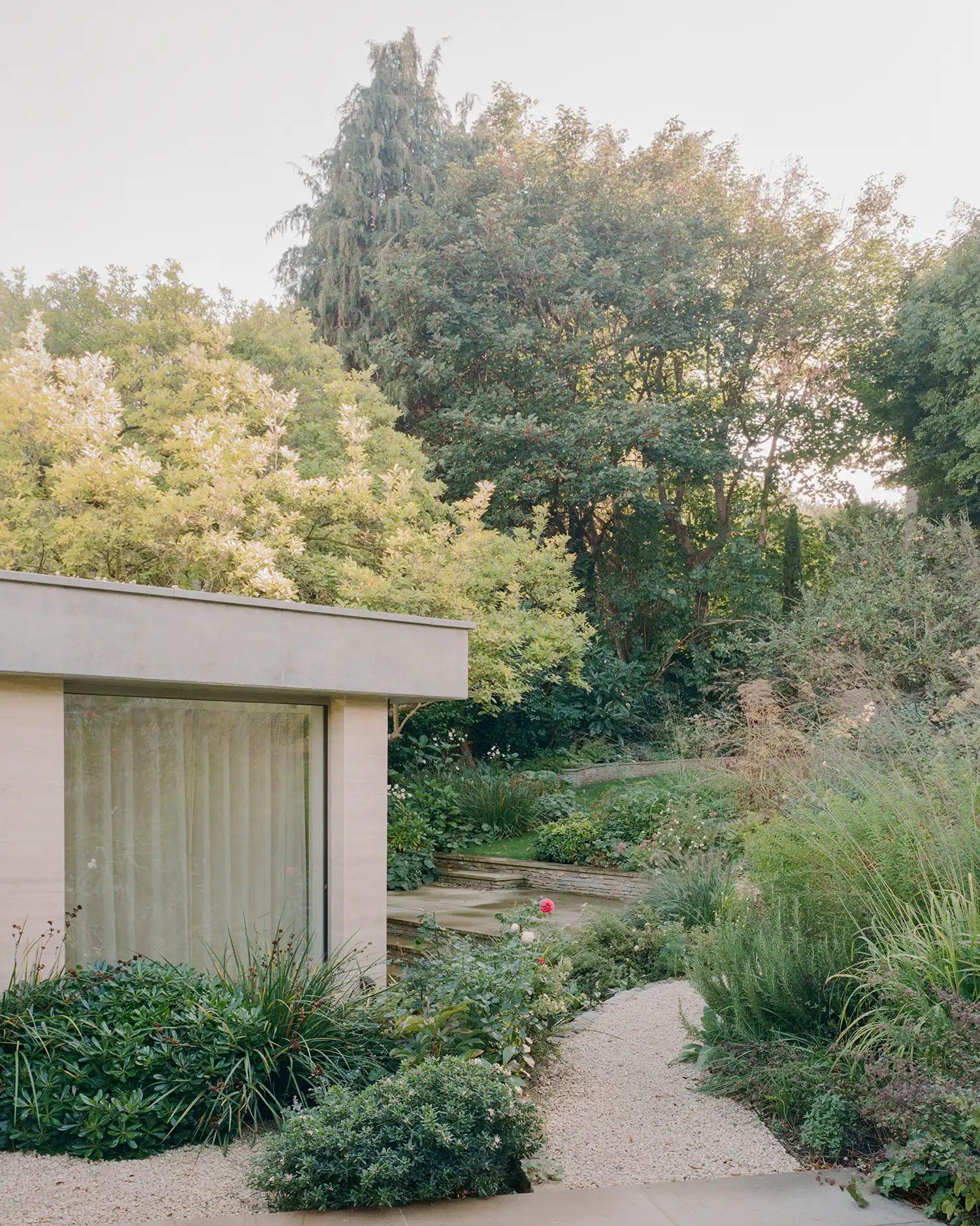 A gravel path winding through a heavily landscaped garden toward a stone-clad building in Highgate.