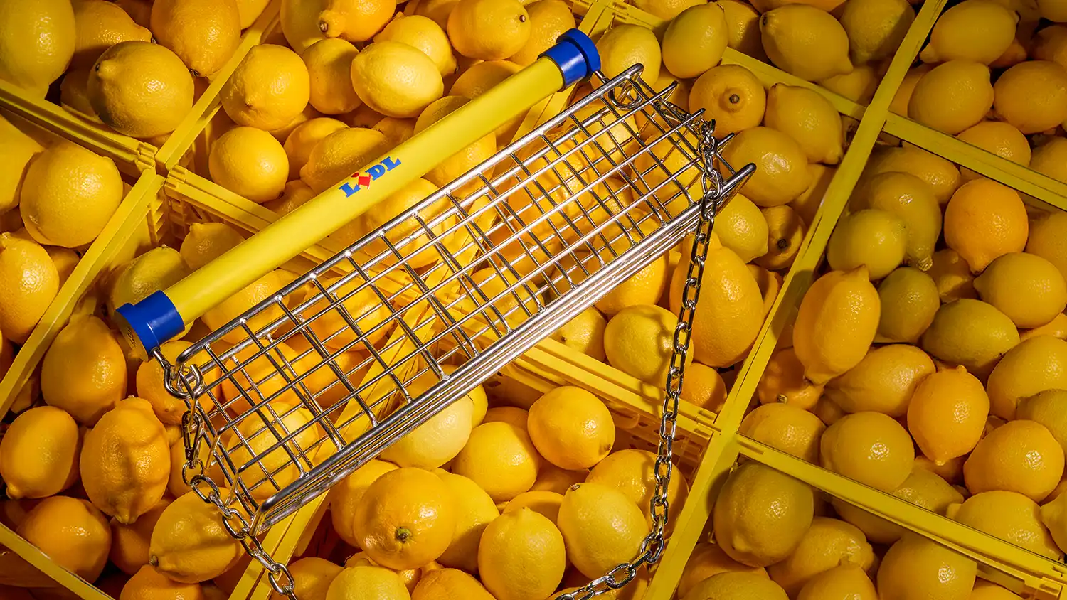 Top-down perspective of the Lidl x Nik Bentel bag placed atop a sea of fresh lemons in yellow crates.