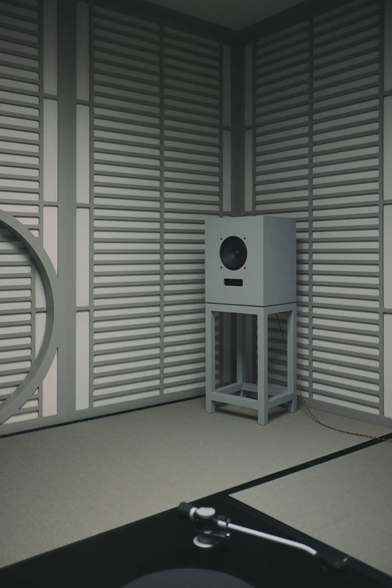 A medium-sized Rokujo speaker stands on a minimalist stand, demonstrating precision craftsmanship.