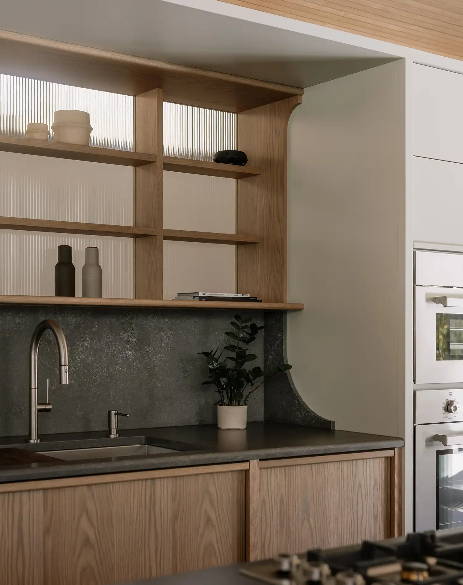 Detail of custom wooden kitchen cabinetry with fluted glass accents in Perchée house.