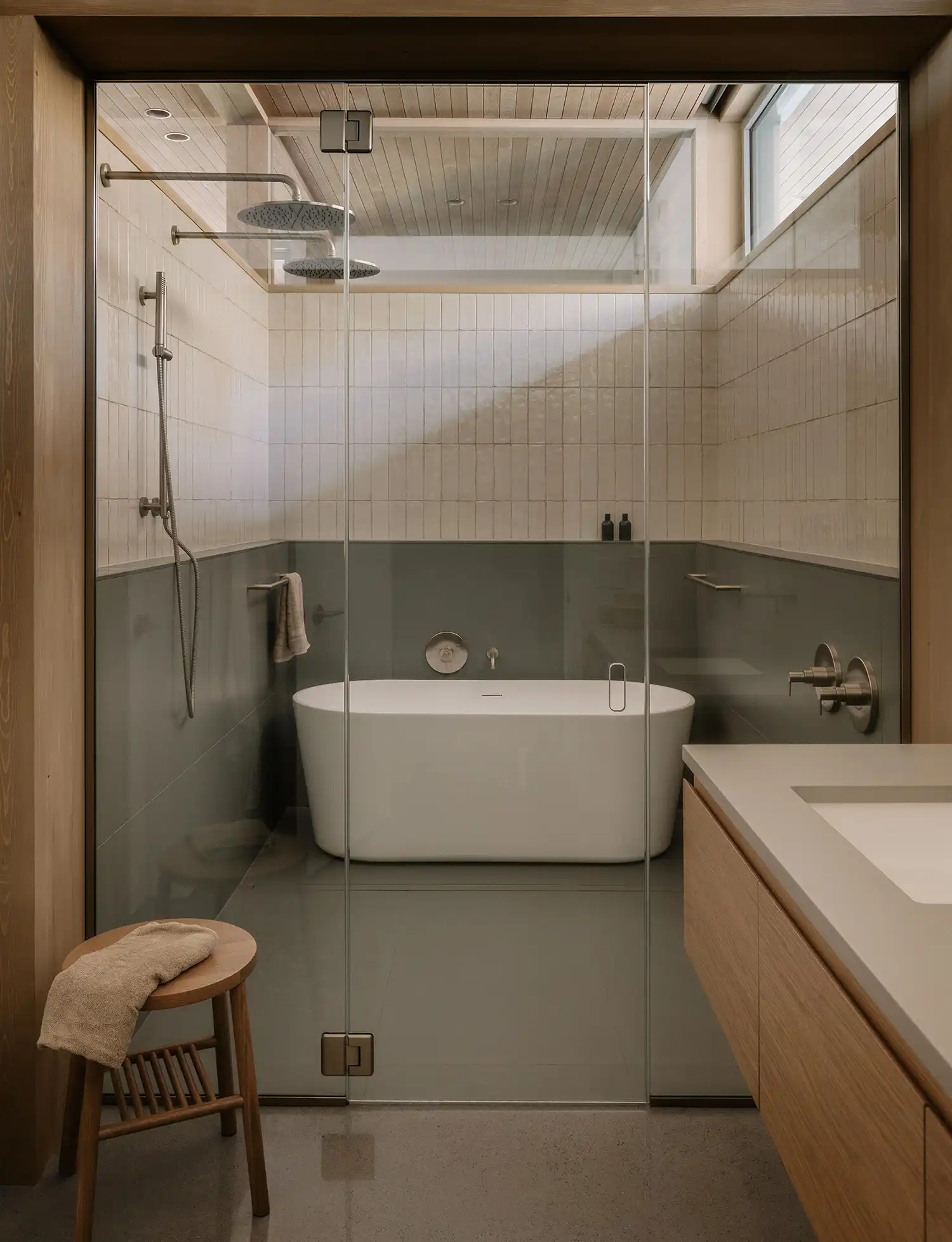 Modern bathroom at Perchée house with a glass-enclosed wet room and a freestanding tub.