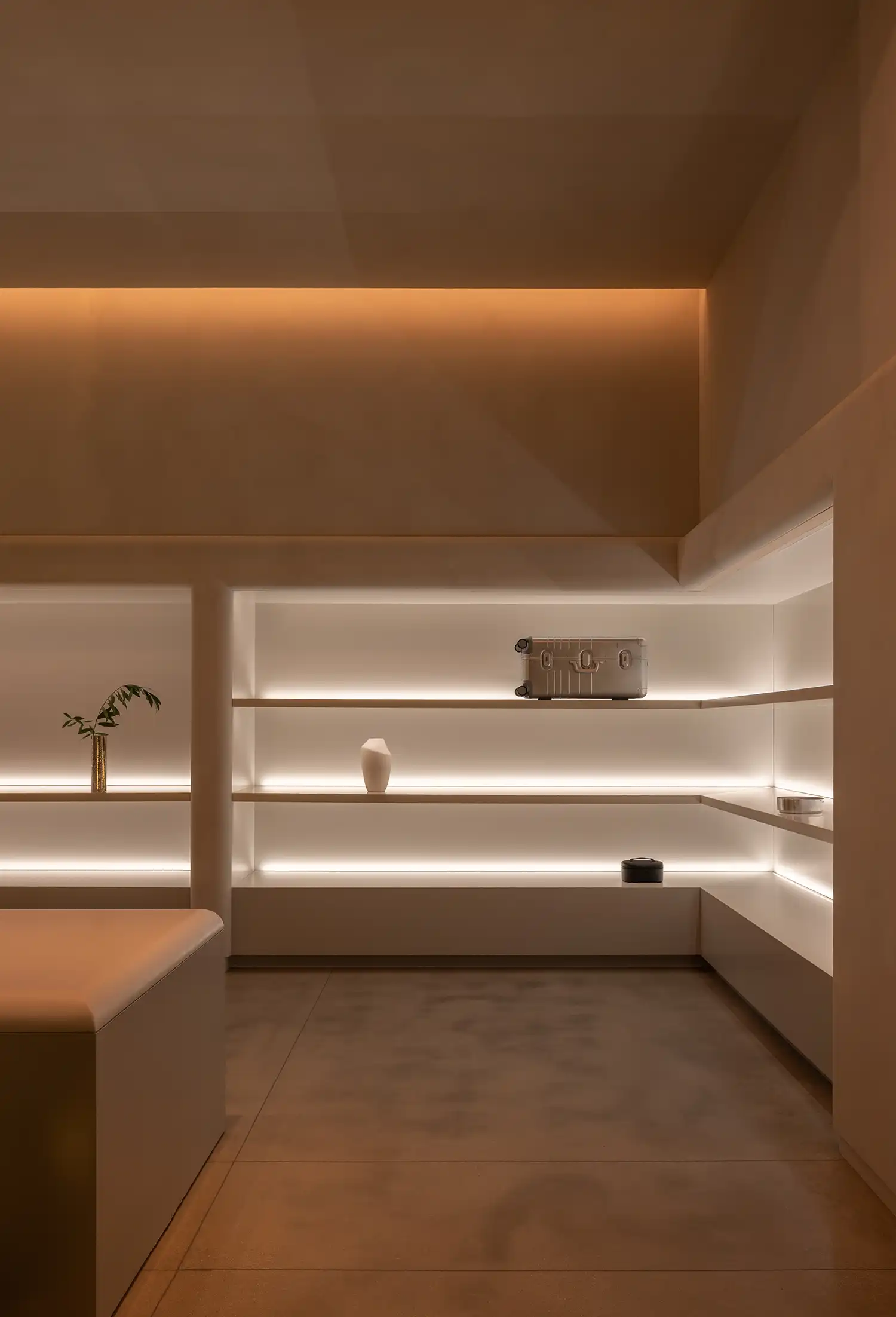 Minimalist Monos retail space with recessed backlit shelving and limewashed walls.