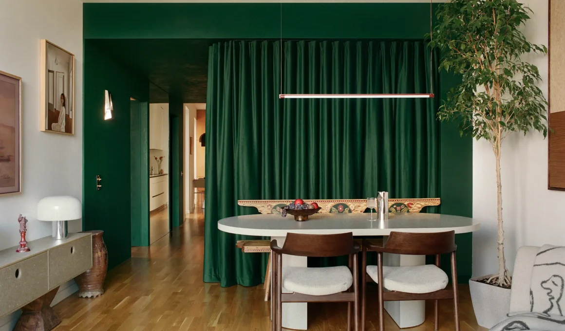 Open-plan dining area with a green velvet curtain divider and traditional hand-painted bench.