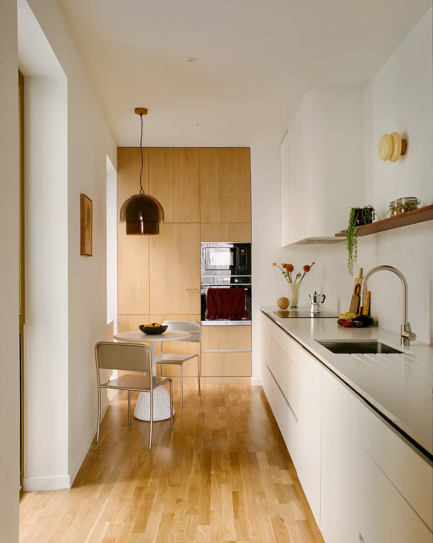 Minimalist galley kitchen with light wood cabinetry and a small breakfast nook.