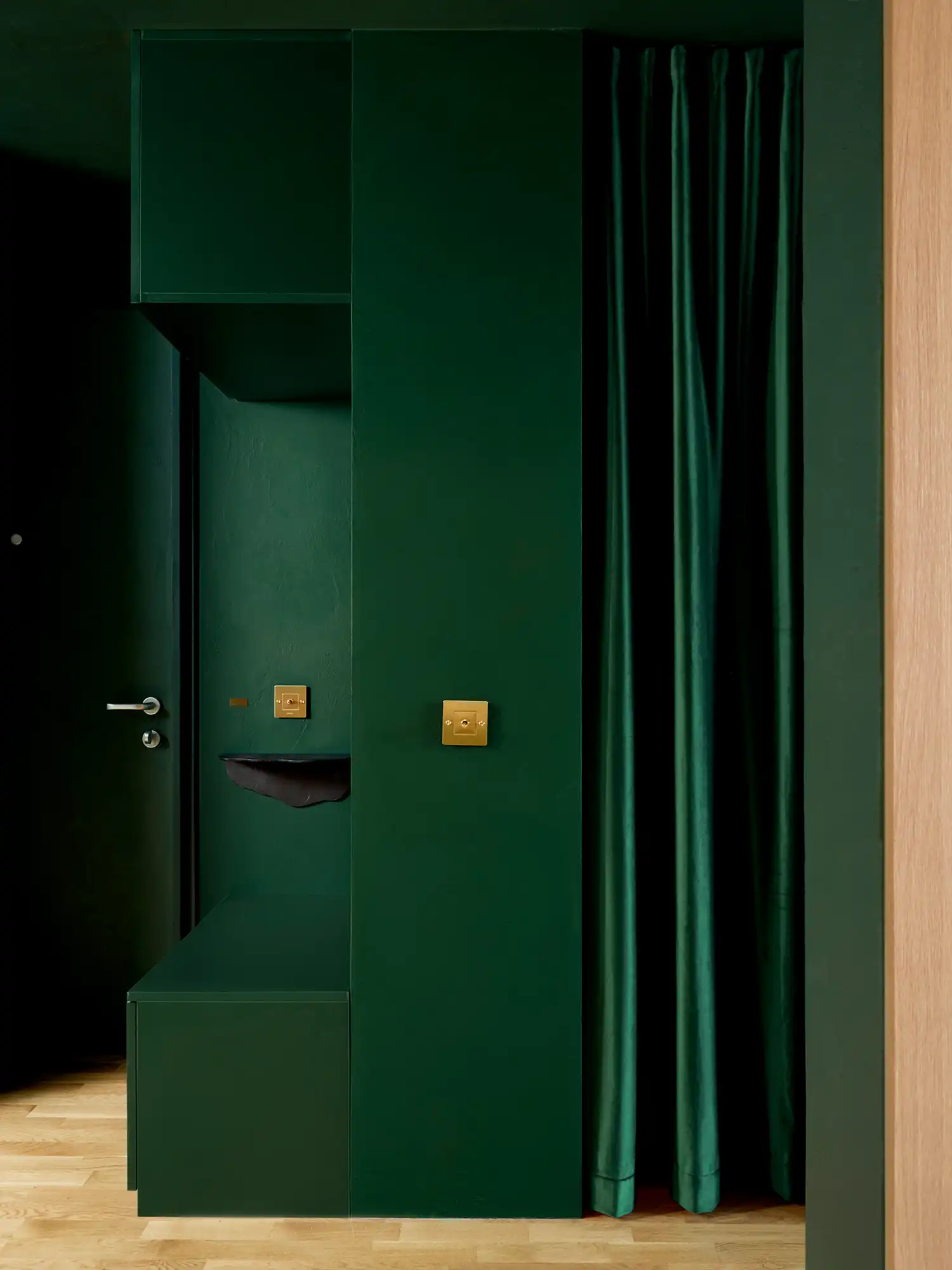 Detail of the green entrance "box" with brass light switches and an integrated green curtain.
