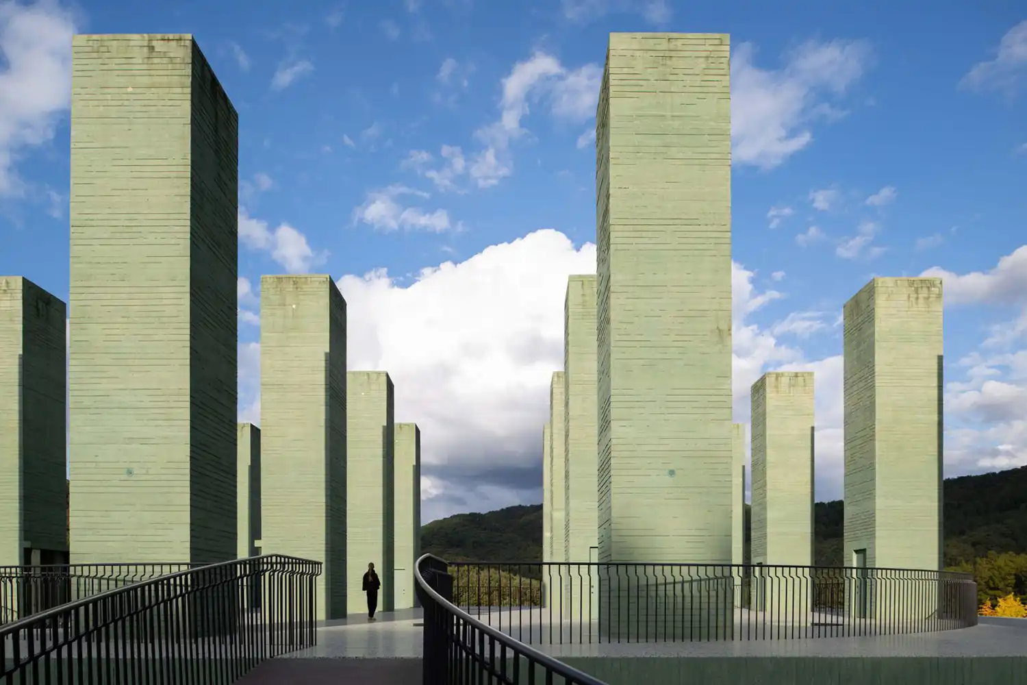 Obelisk-like green concrete columns on the roof terrace of REST