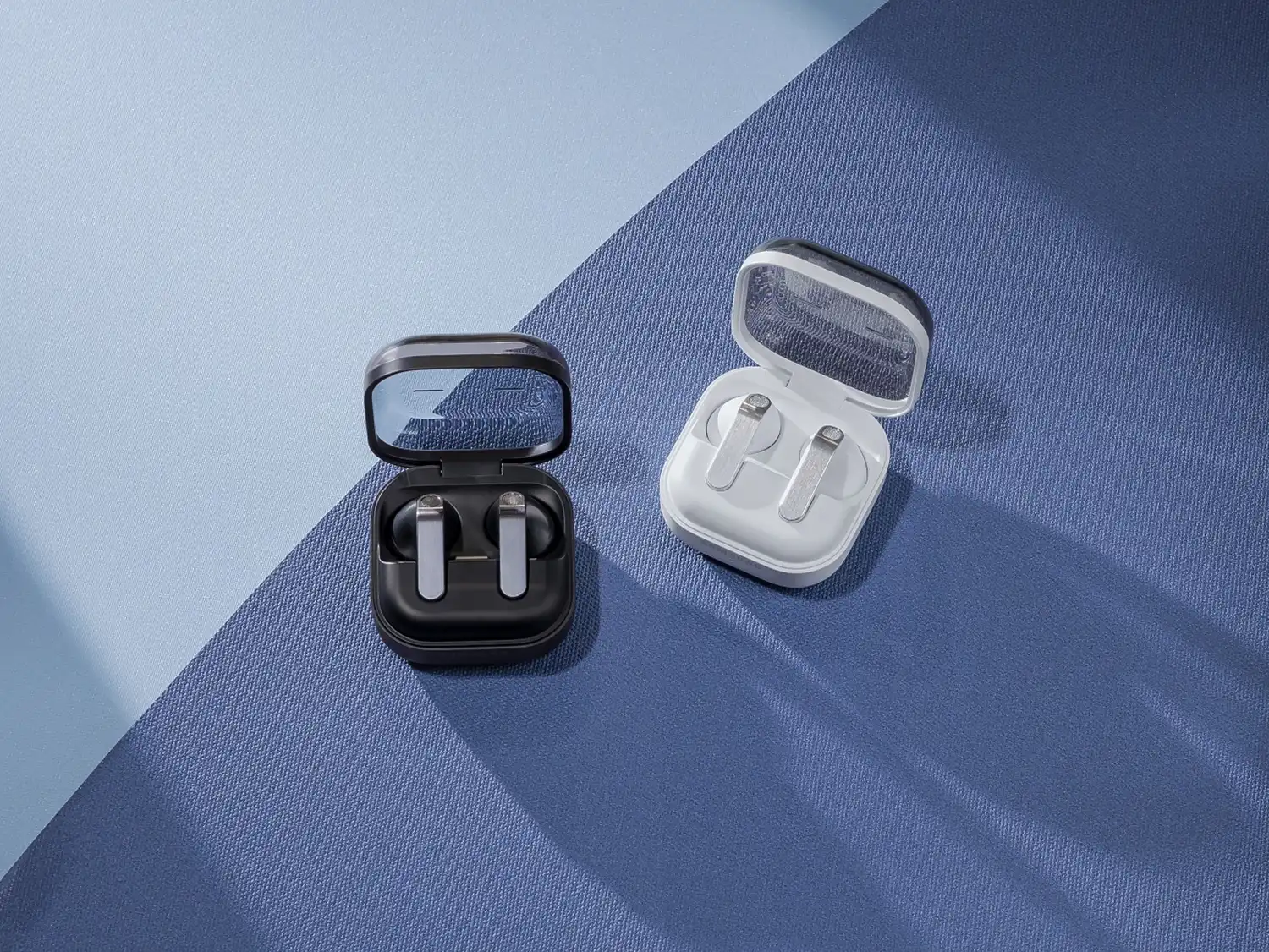 Close-up of Galaxy Buds4 Pro in Black and White charging cases with "blade" design.