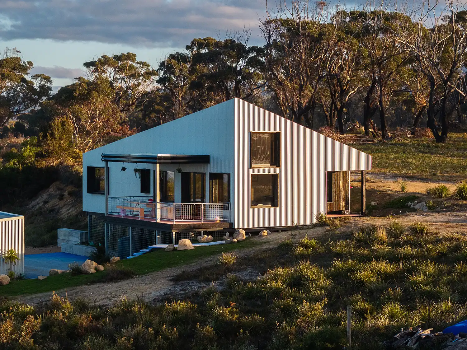 Aerial view of the single-level Scamander Passivhaus A with a white metal exterior on a coastal hill.
