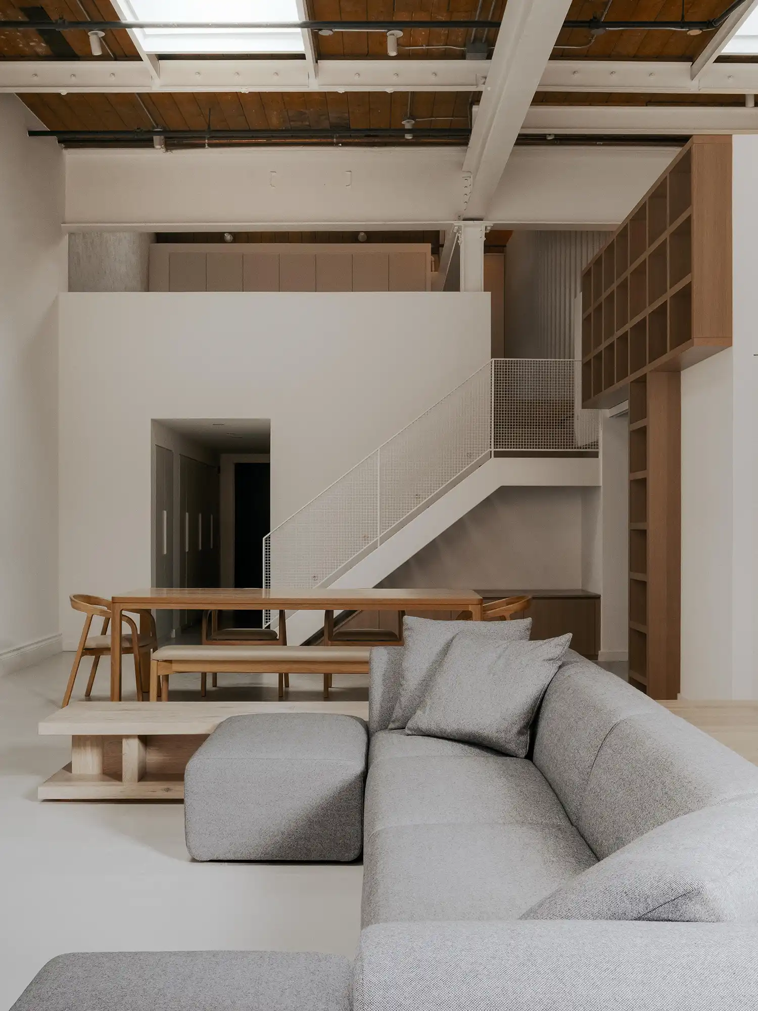Double-height living volume with mezzanine and industrial timber ceiling