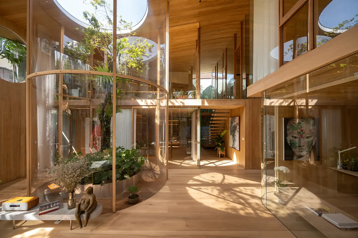 Multi-level interior with glass-enclosed indoor gardens and wooden stairs.