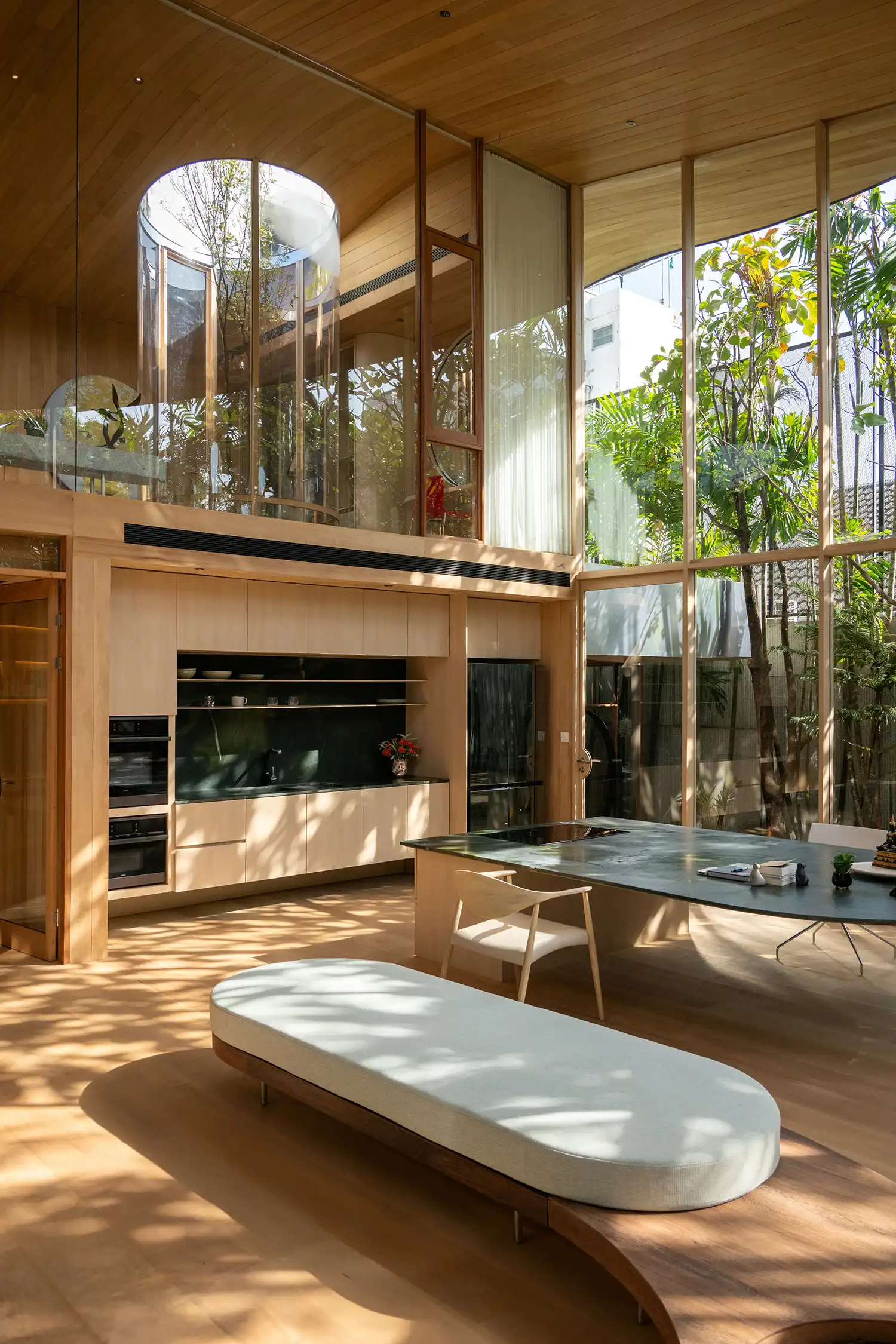 Modern kitchen and dining area with high ceilings and large glass windows.