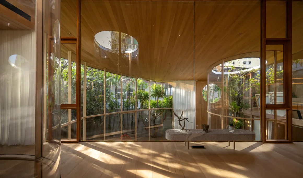 Interior view of a wooden room with curved glass walls and a circular skylight.