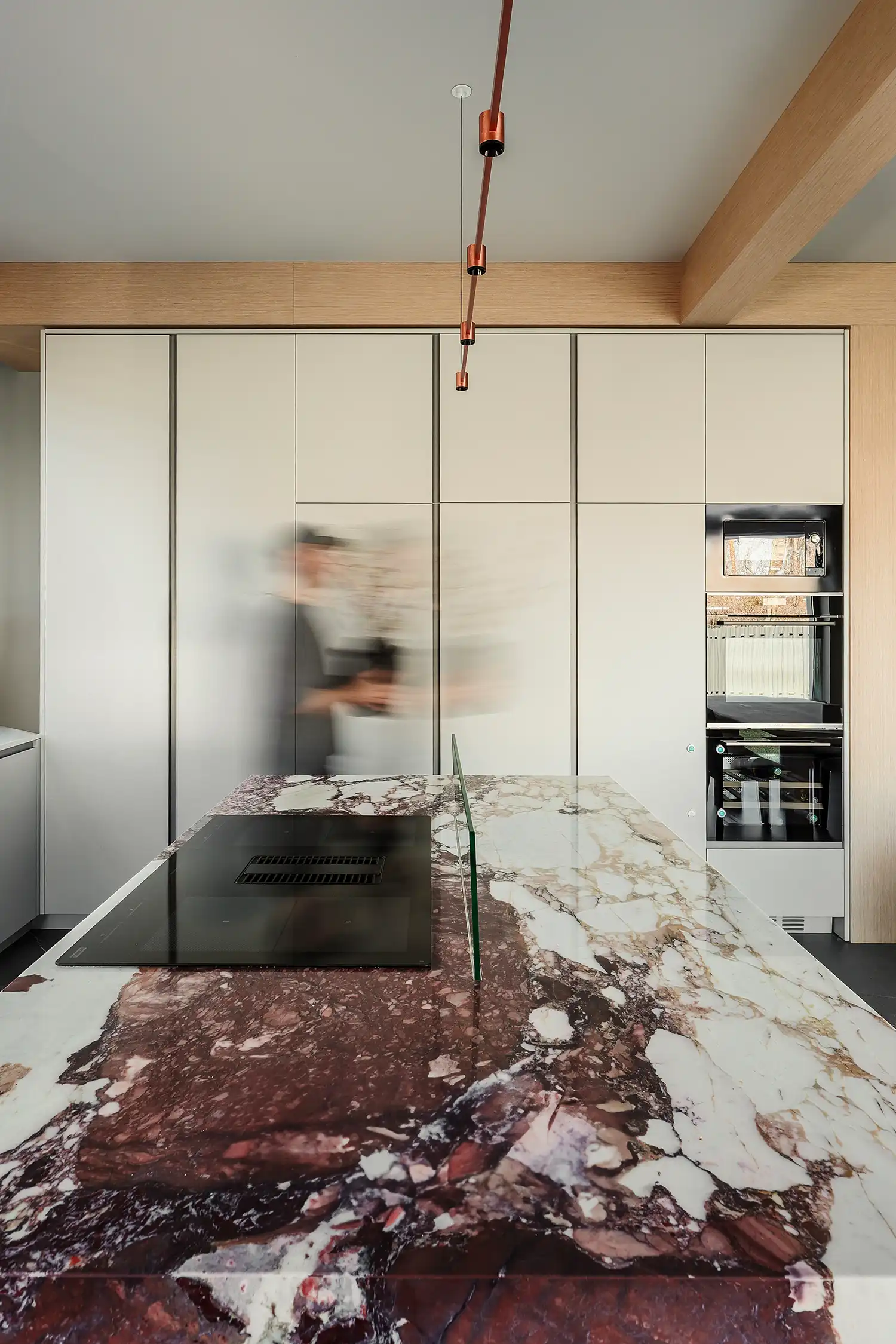 Open-plan kitchen and dining area with light wood ceiling beams and marble island.