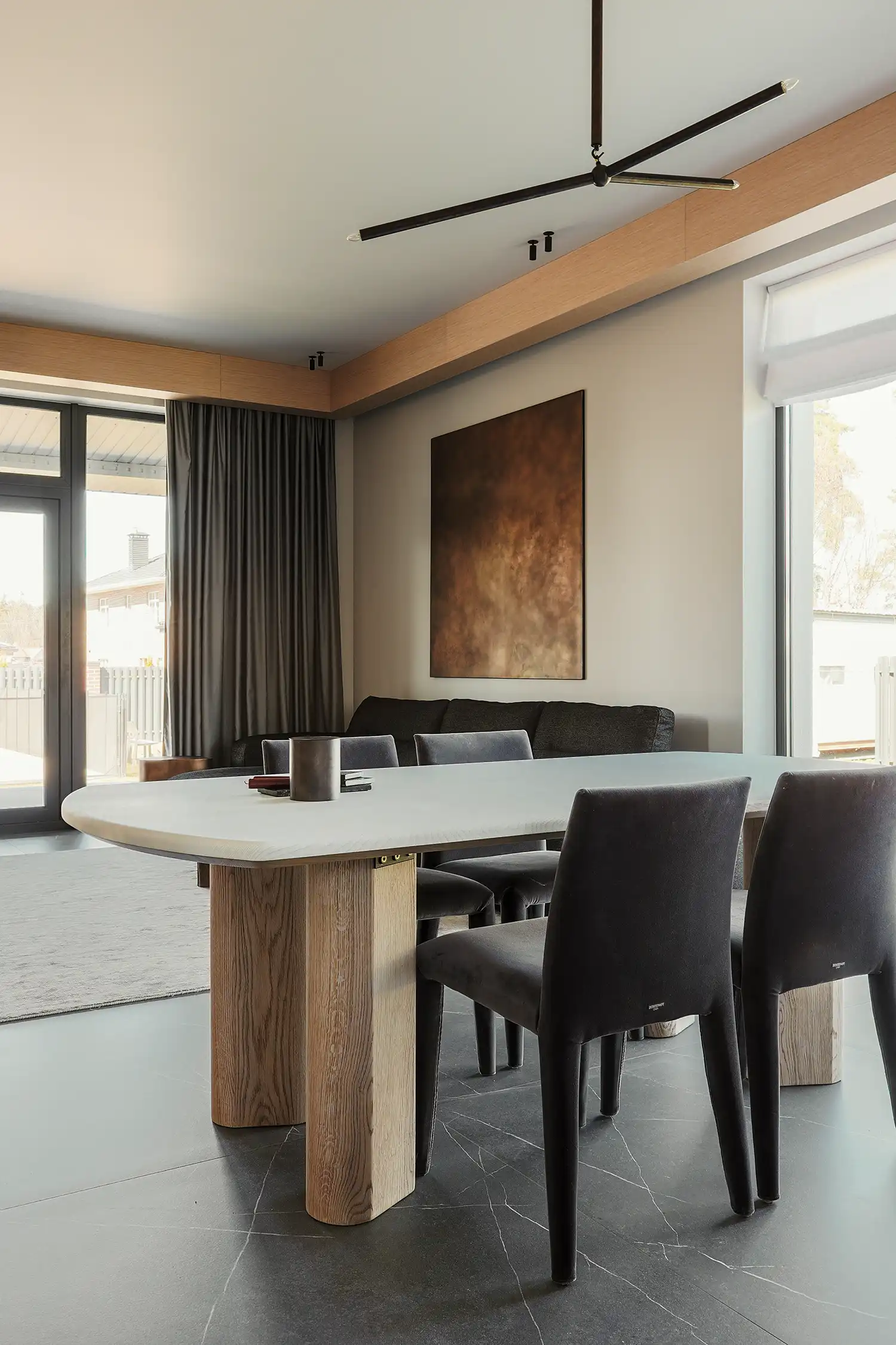 Contemporary living room with a dark sectional sofa, copper-toned art, and wooden ceiling details.