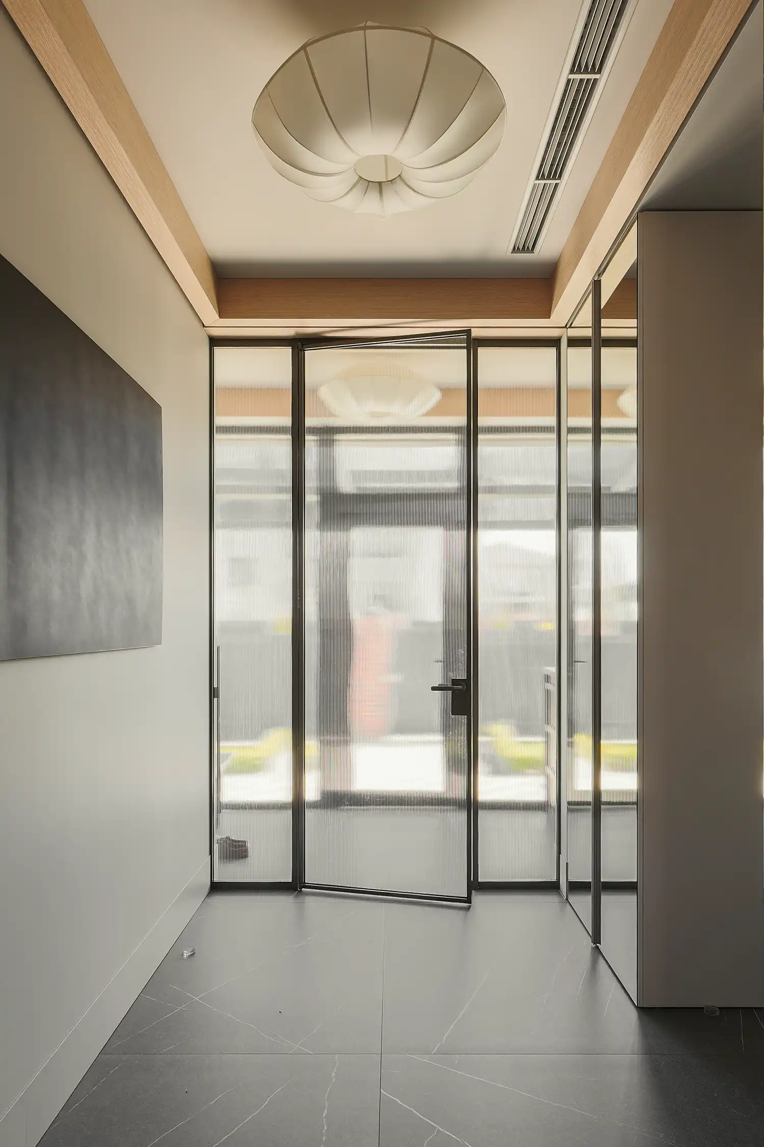 Fluted glass door and mirrored closets in a modern entryway with gray tiled flooring.