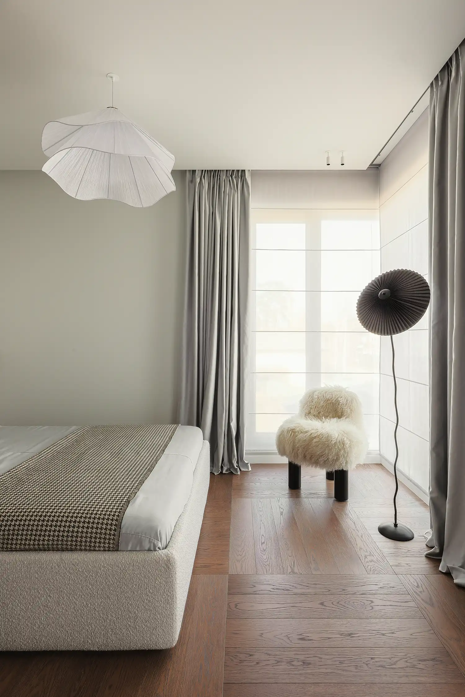 Master bedroom in a Kyiv house featuring a white sheepskin armchair and herringbone parquet.