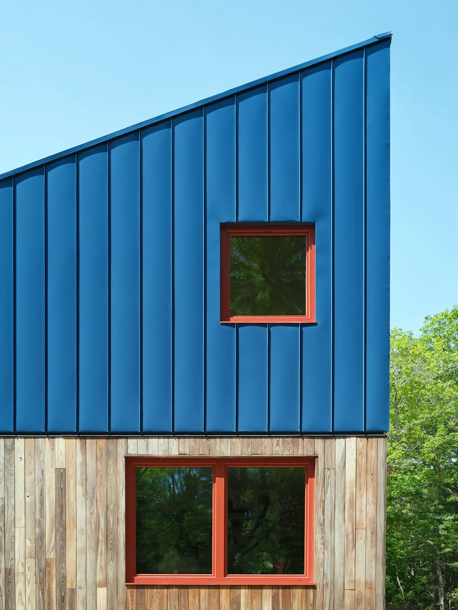 Close-up of the exterior facade showing blue metal siding and wood cladding.