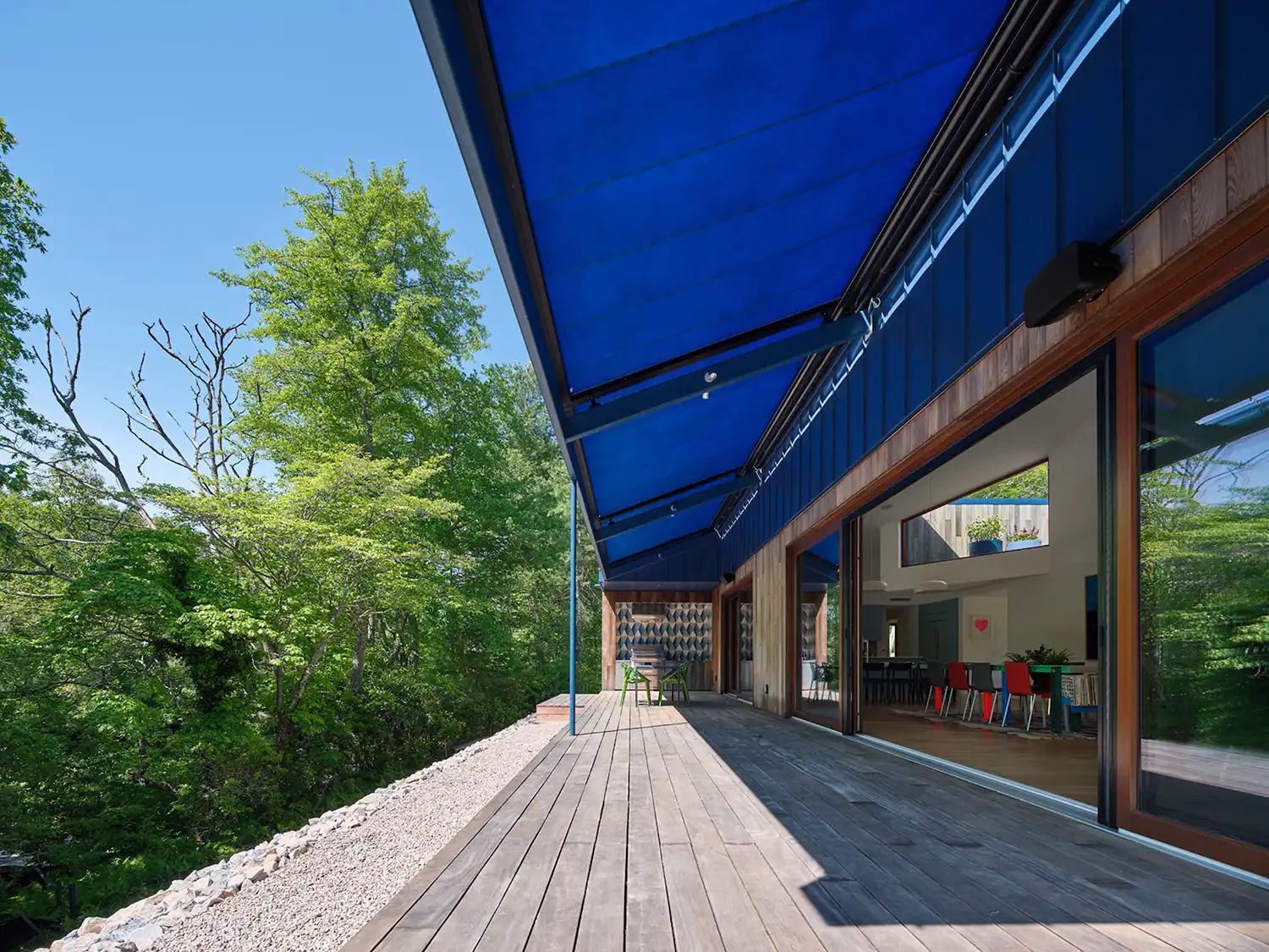 A wide exterior deck with a large blue awning overlooking the river.