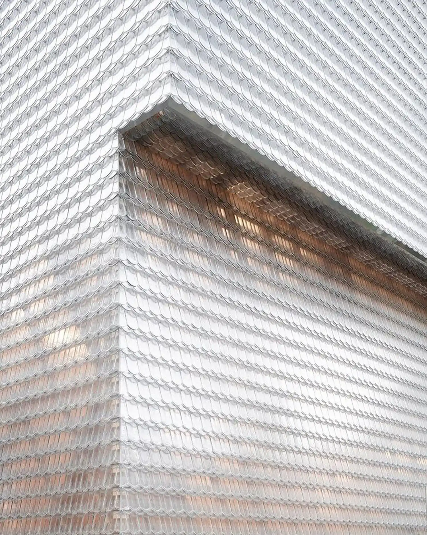 Close-up of the corner of a building clad in overlapping cast-glass beaver-tail shingles.